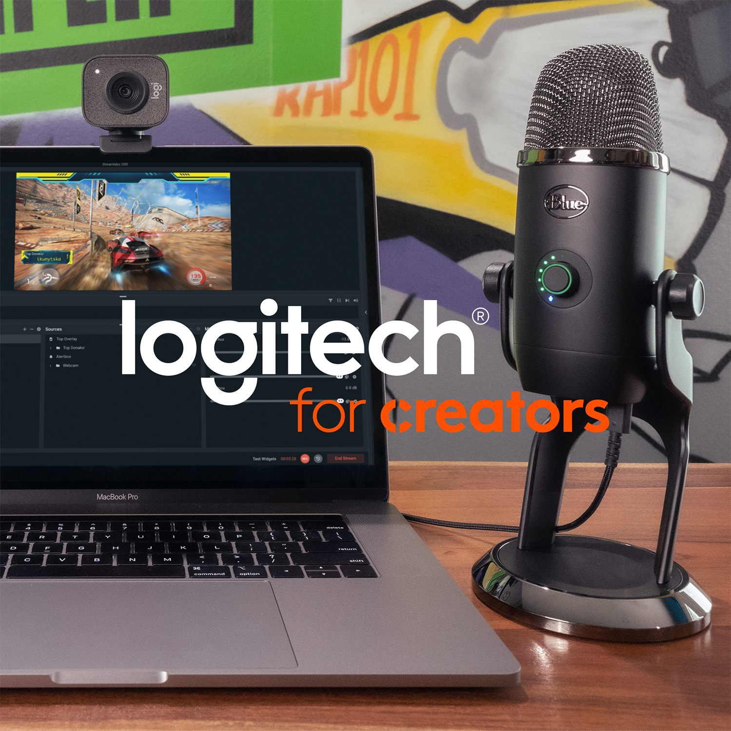 Logitech setup: webcam, microphone, laptop displaying a game. The setup is on a wooden table.