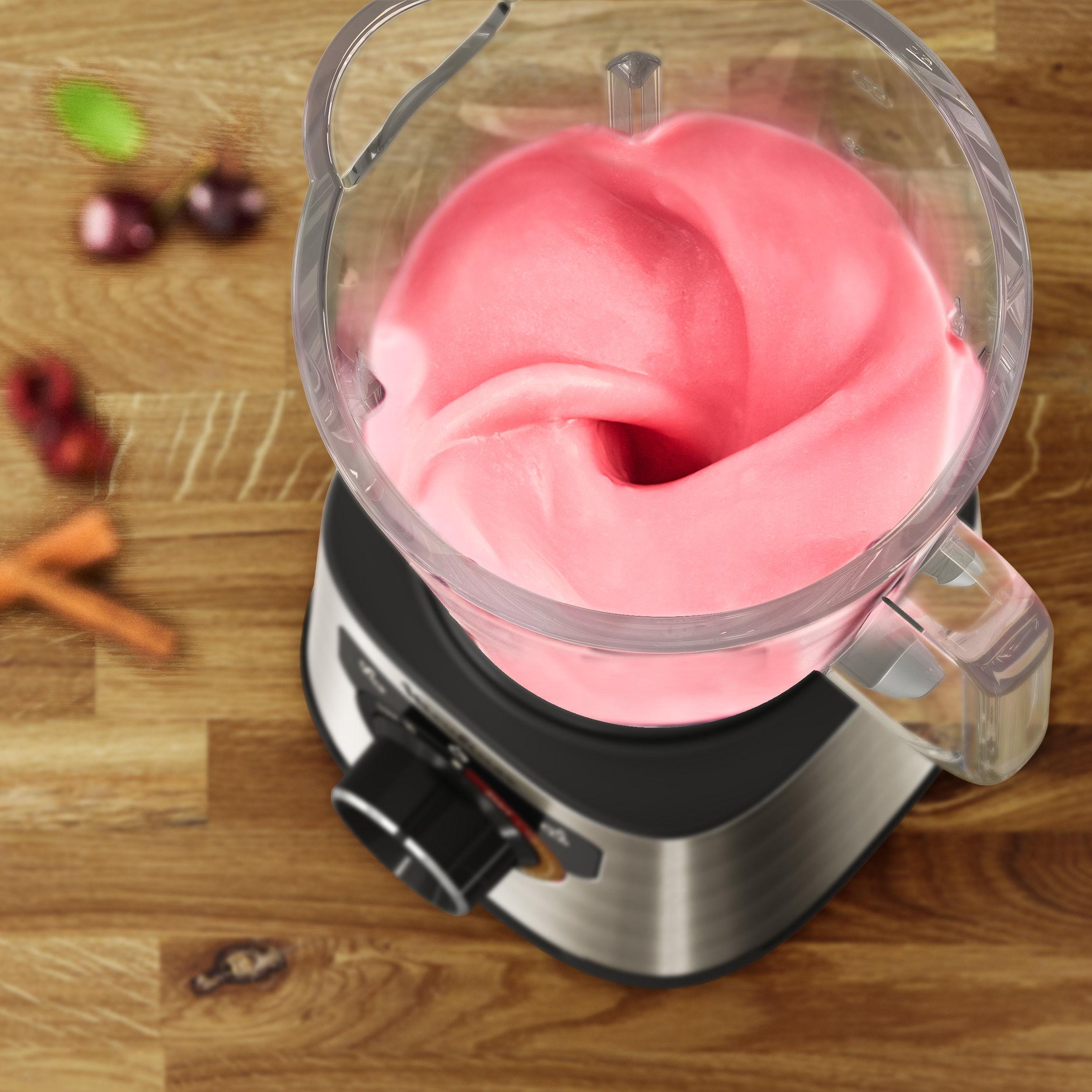 Mixer mit rosa Smoothie im Inneren. Der Mixer steht auf einem Holztisch.