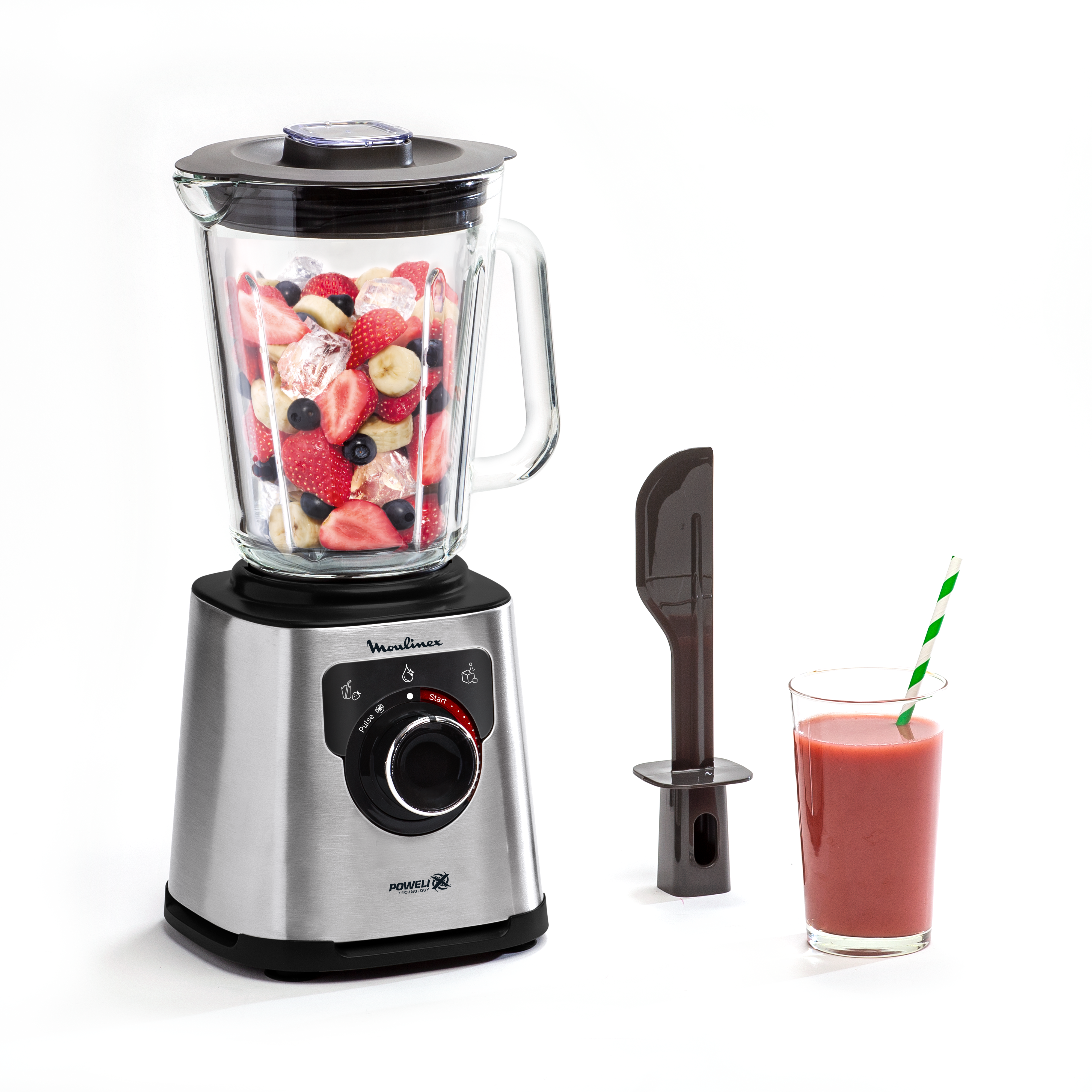 Ein silberner Mixer mit Früchten und Eis, ein Spatel und ein Glas Smoothie.