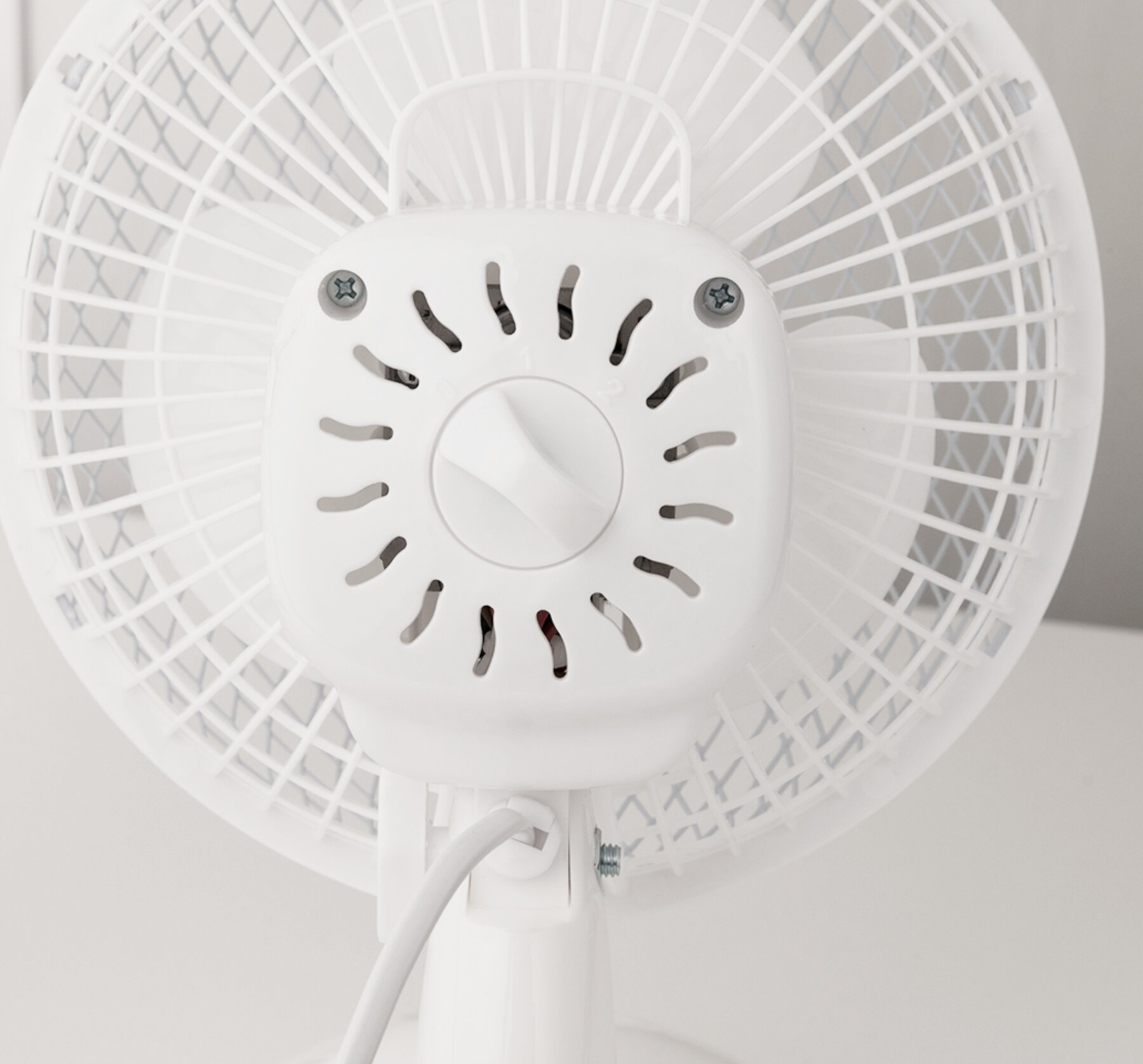 Egy fehér elektromos ventilátor hátulnézete, láthatóak a lapátok és a vezérlőtárcsa.