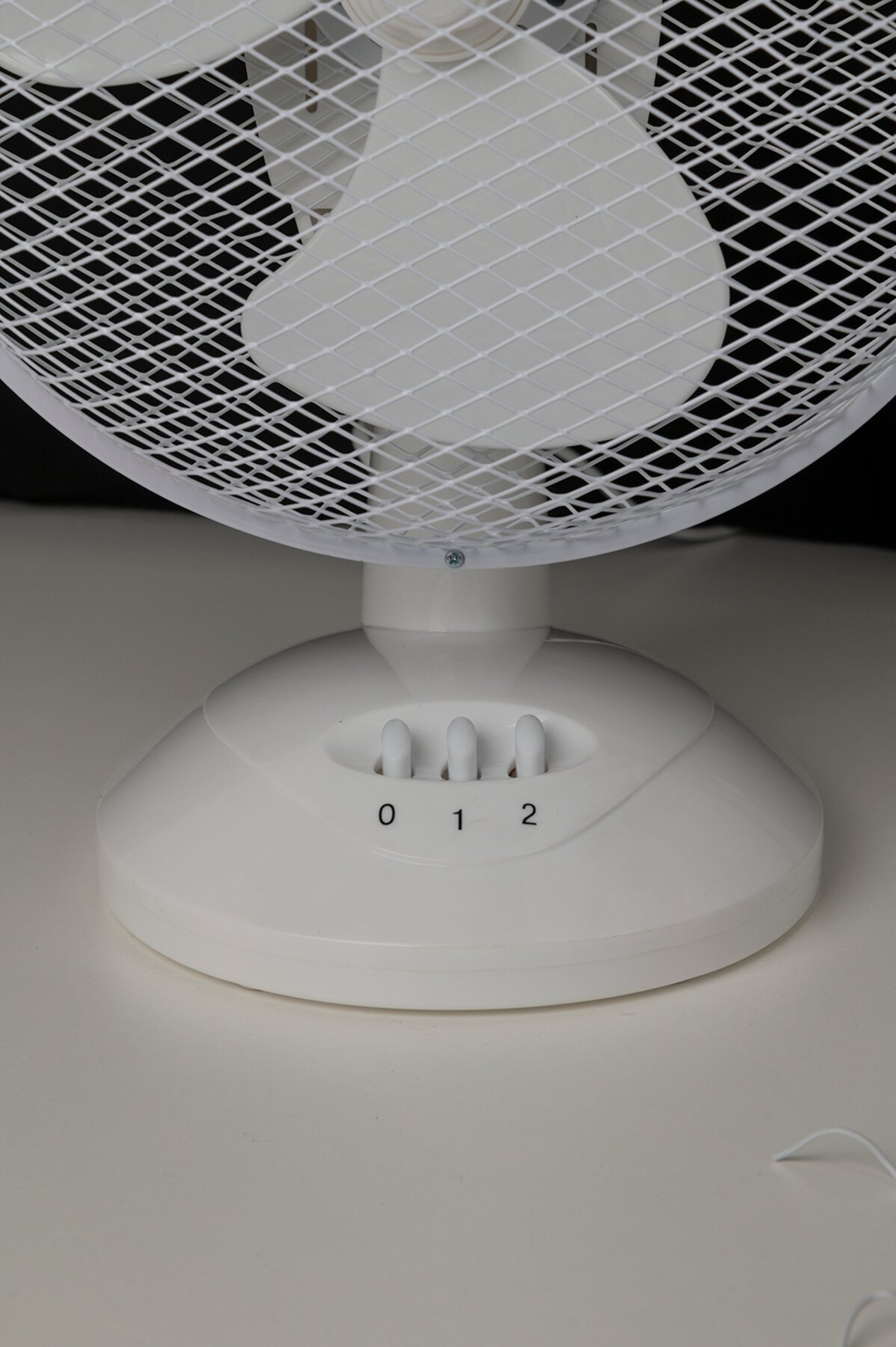Fehér asztali ventilátor védőráccsal és három sebességbeállítással, 0, 1 és 2 felirattal.