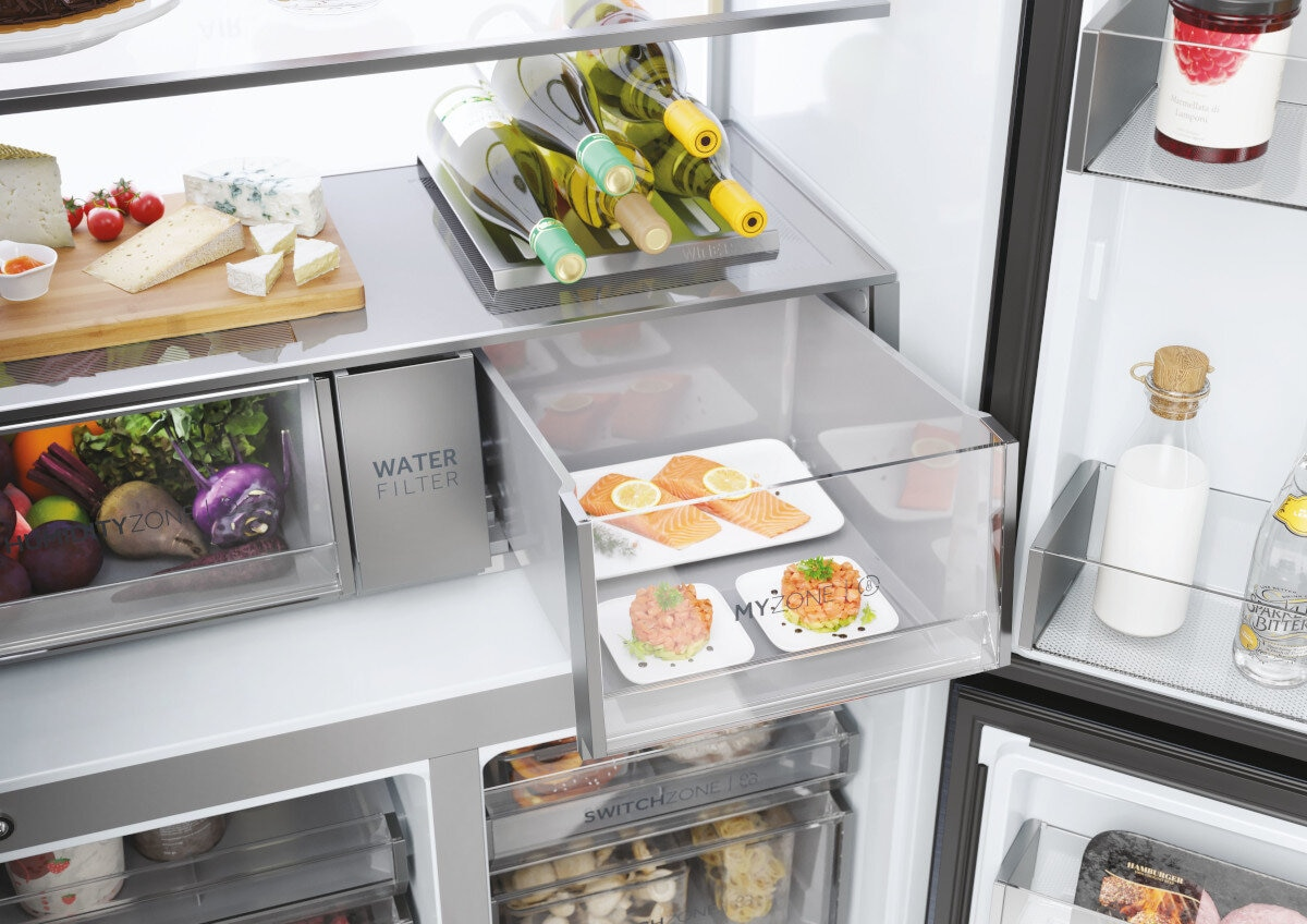 Wewnątrz lodówki: półki z produktami spożywczymi, w tym winem, łososiem i warzywami.