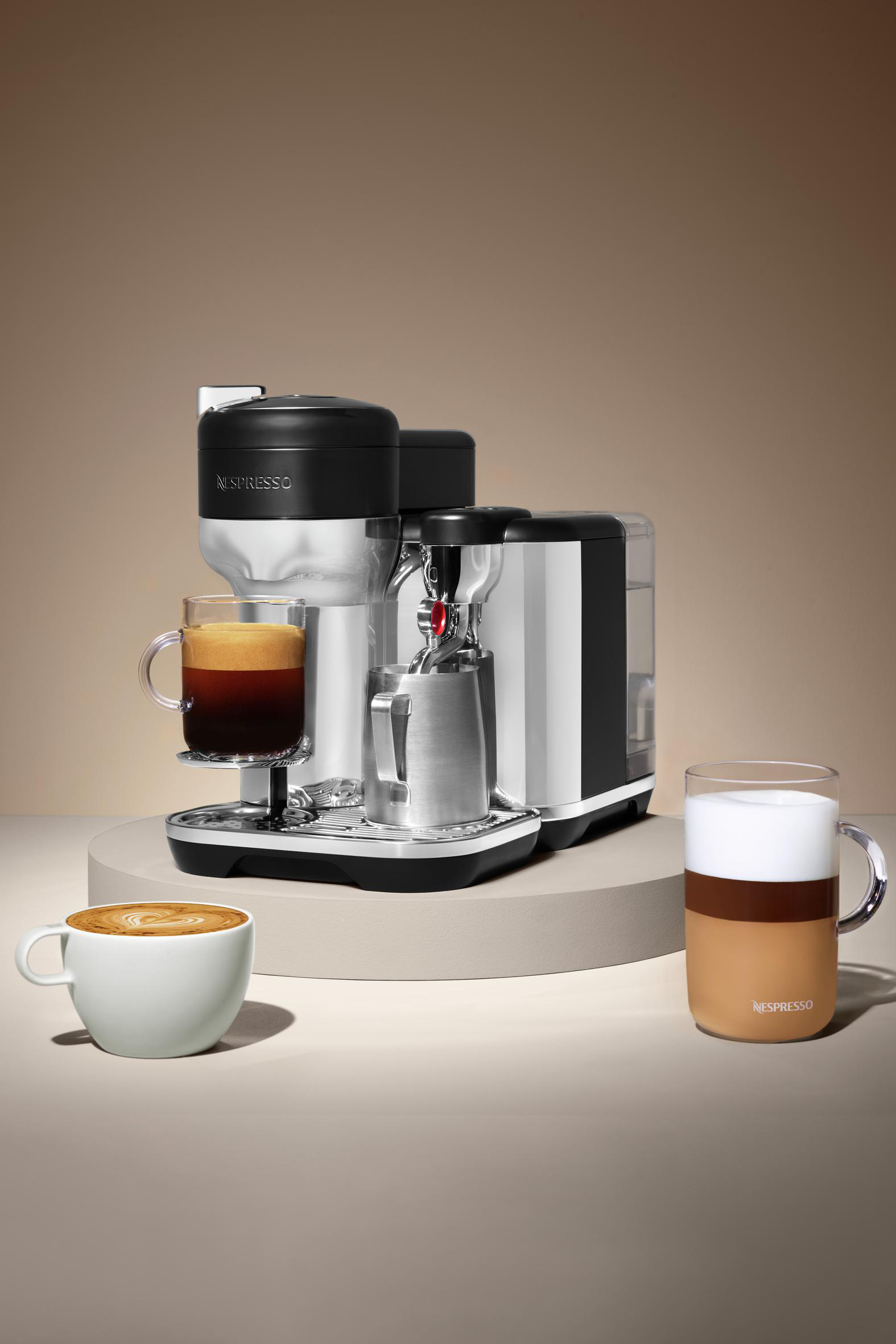 Nespresso-Kaffeemaschine mit zwei Kaffeetassen. Kaffeetassen auf beiger Oberfläche. Weißer Hintergrund.