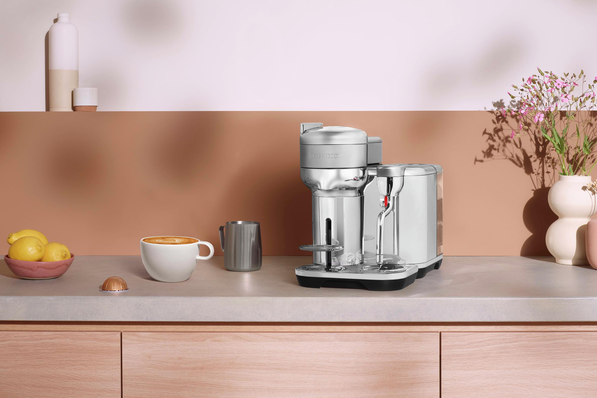 Kaffeemaschine auf einer Arbeitsplatte mit einer Tasse Kaffee und anderen Gegenständen.