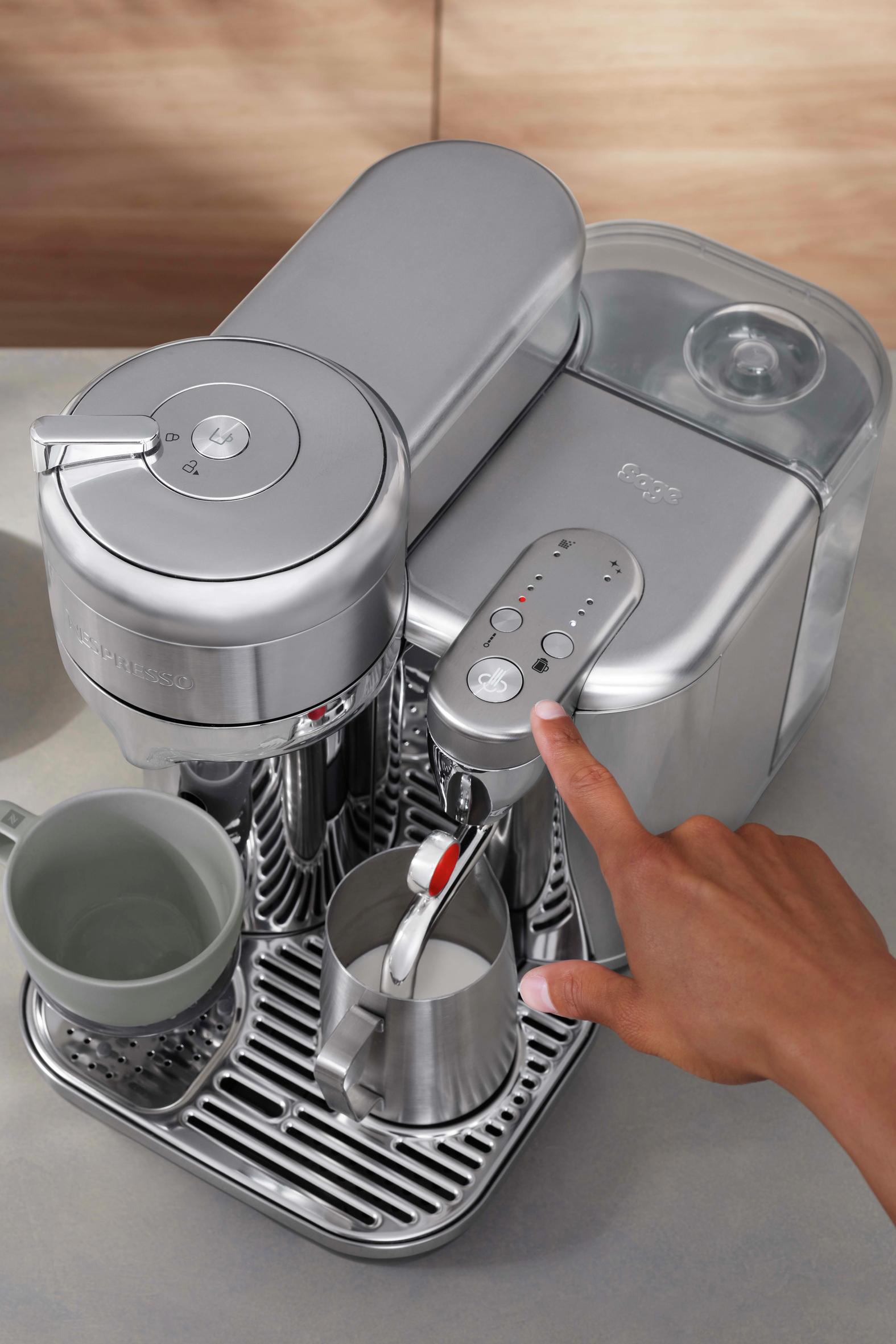 Silberne Espressomaschine mit einer Hand, die einen Knopf drückt.