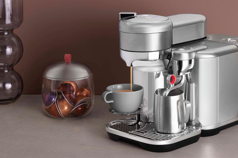 Espressomaschine, die Kaffee in eine Tasse ausgibt, mit einem Glas Kapseln daneben.