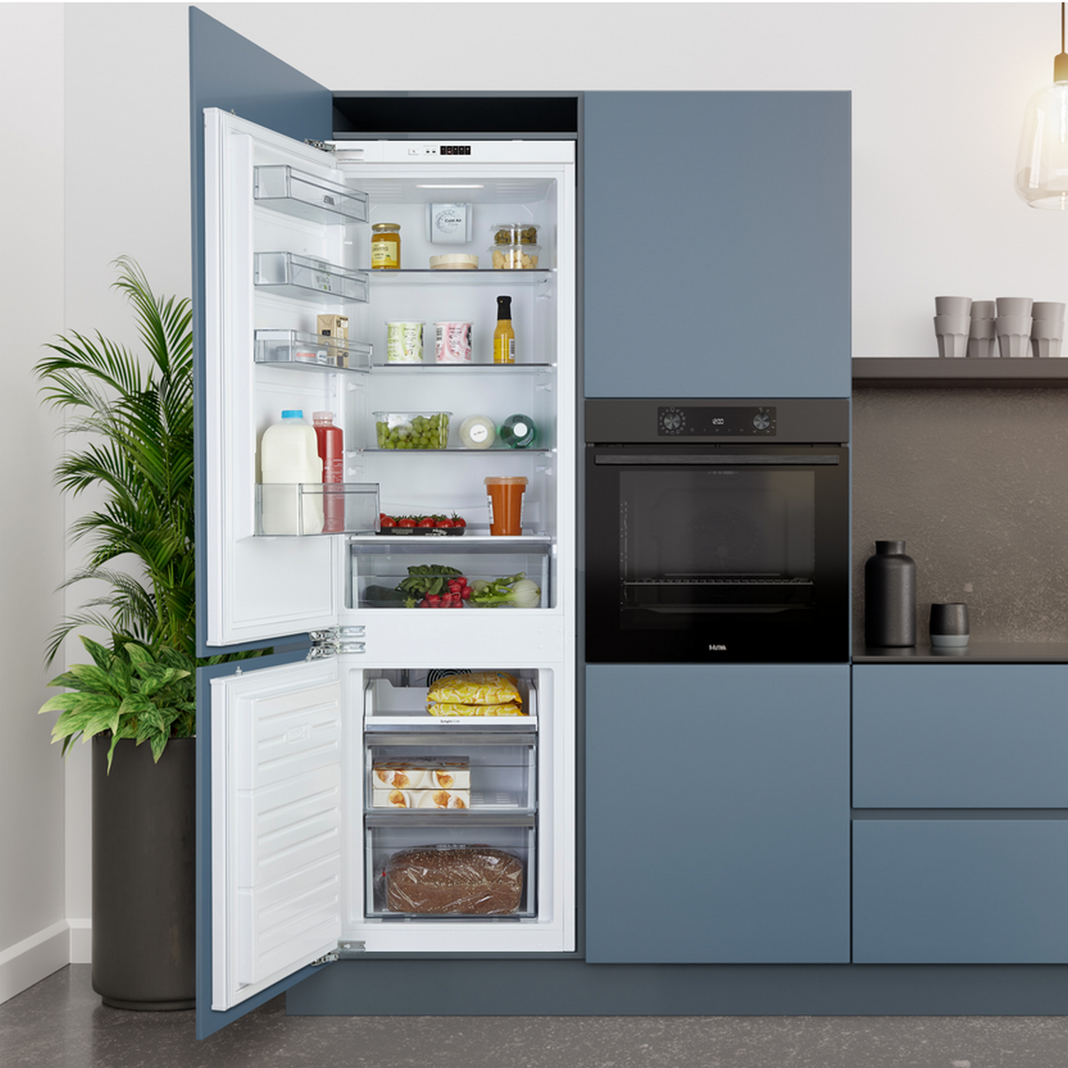 Open refrigerator and freezer. Refrigerator has food items. Blue cabinets and dark gray oven.