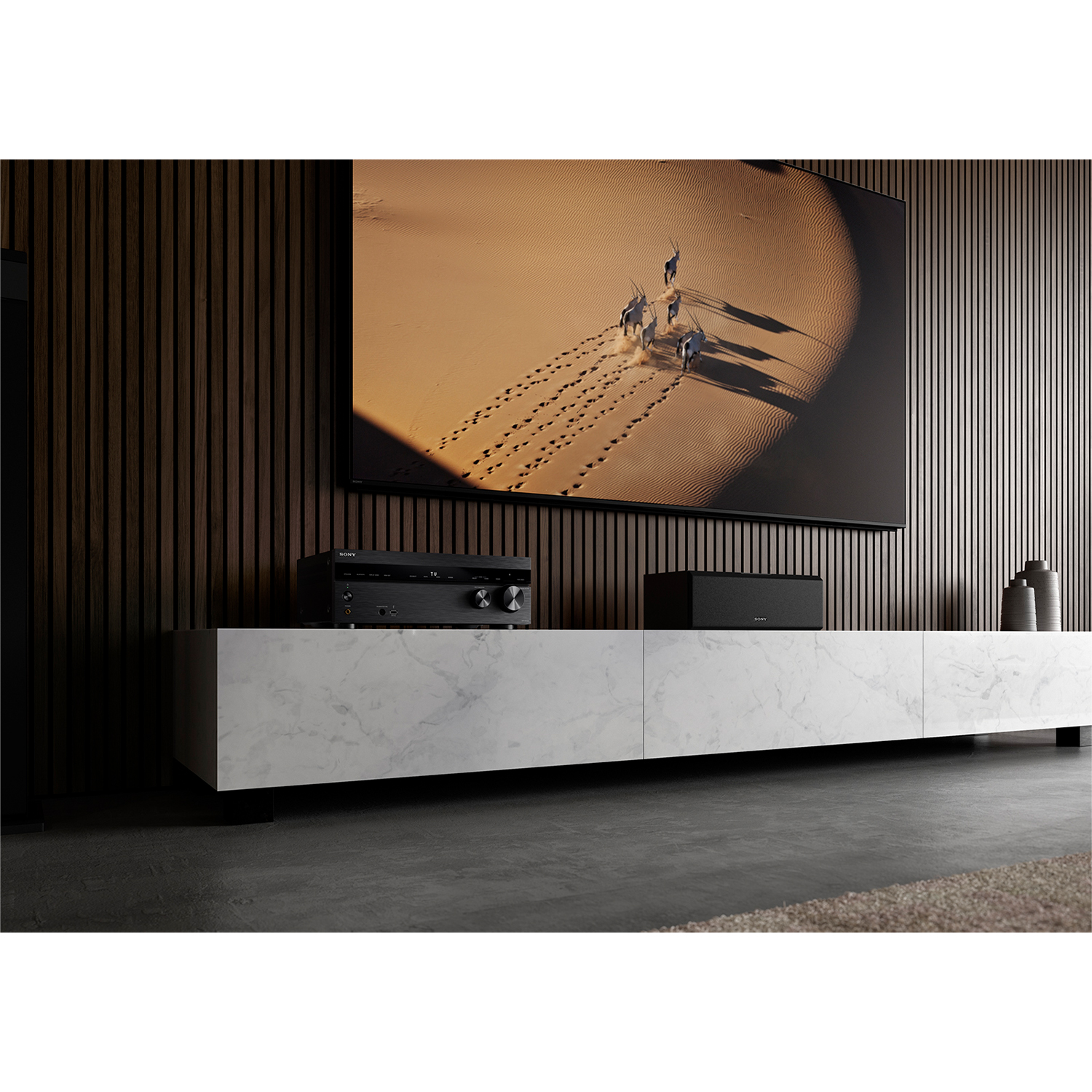 Soggiorno con TV grande, soundbar e mobile in marmo bianco.