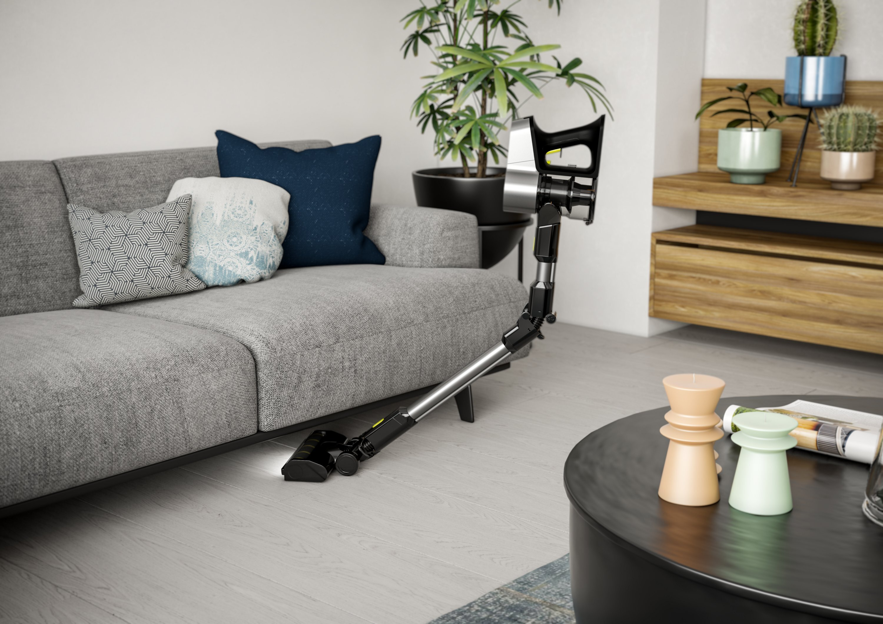 Pokój z szarą kanapą, odkurzaczem i okrągłym stolikiem kawowym.