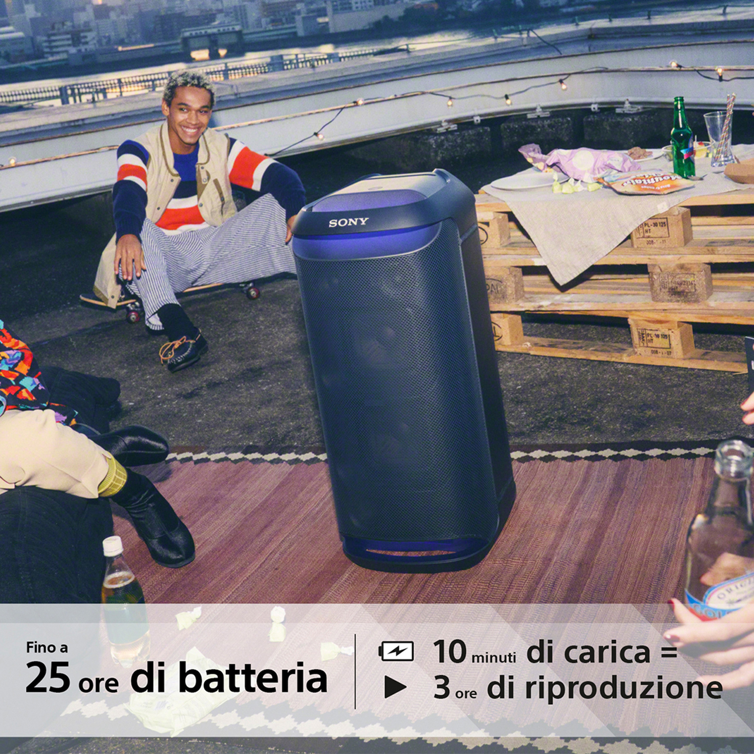 Un gruppo di persone è su un tetto. Un altoparlante è in primo piano con una bottiglia di birra.