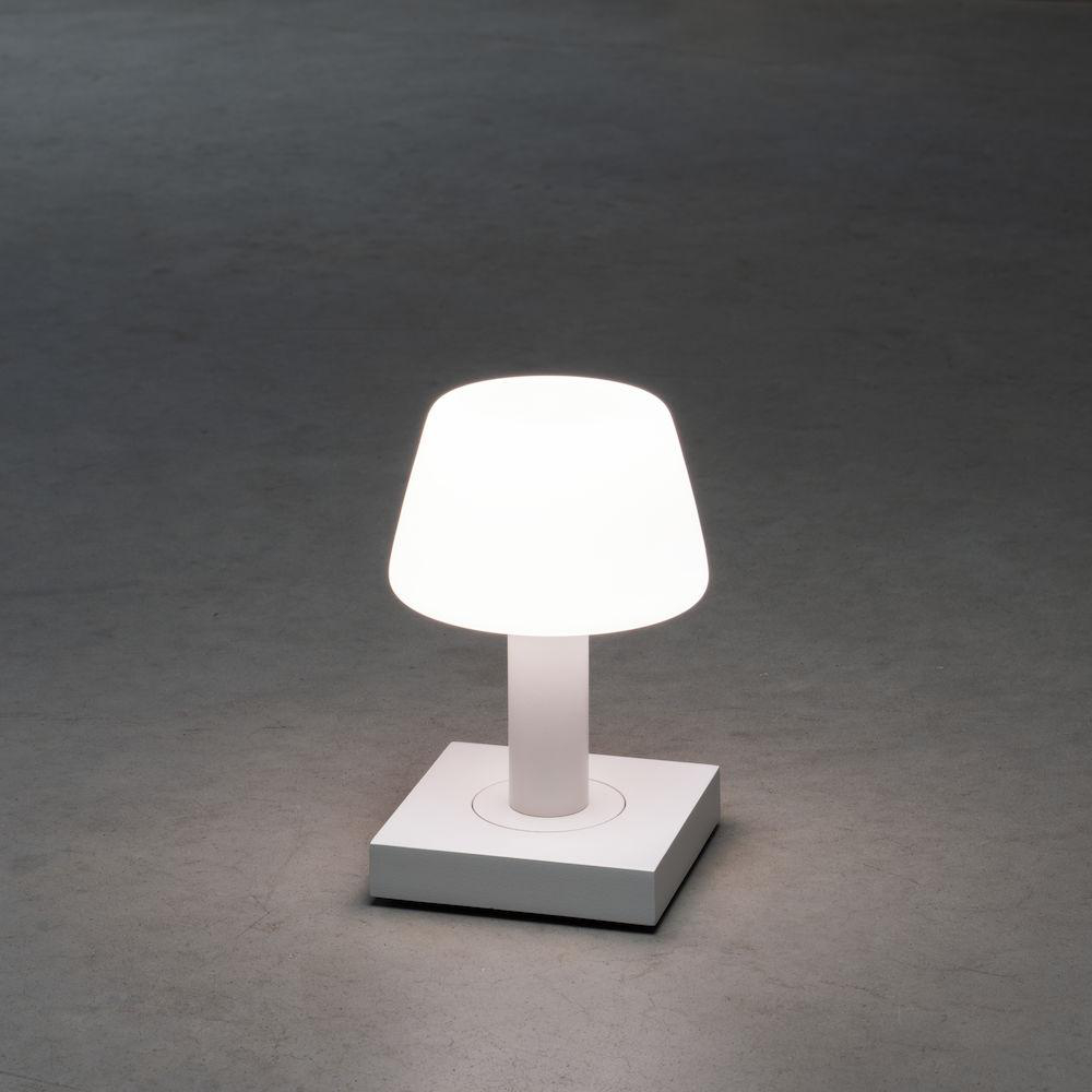 Eine weiße Lampe auf einem weißen Ständer vor grauem Hintergrund.