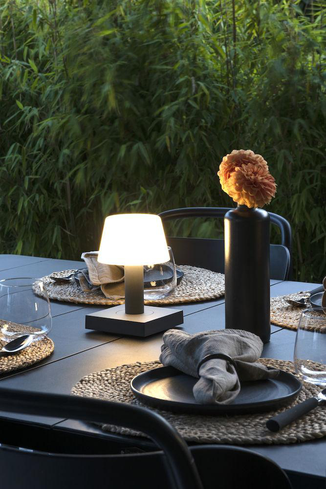 Ein gedeckter Tisch, mit Lampe und Blumen.