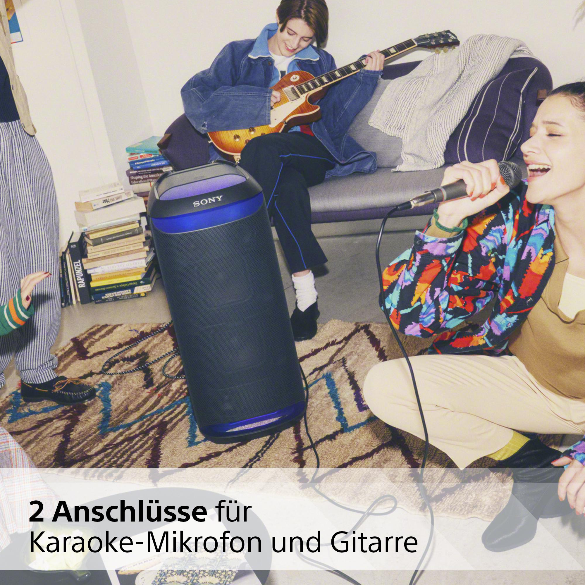Gruppe von Personen mit Lautsprecher und Gitarre, die in ein Mikrofon singen.