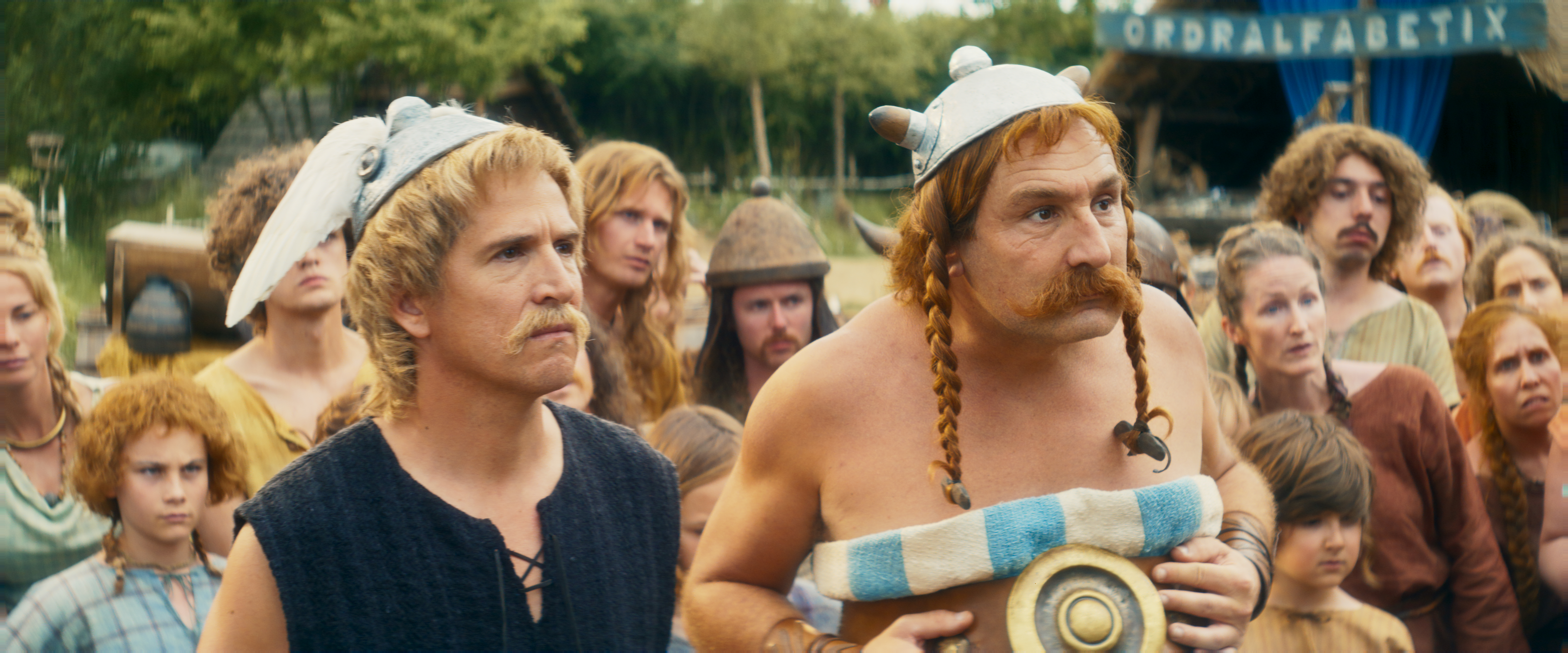 Zwei Männer in Helmen und Kostümen aus einem Film, mit einer Menschenmenge im Hintergrund.