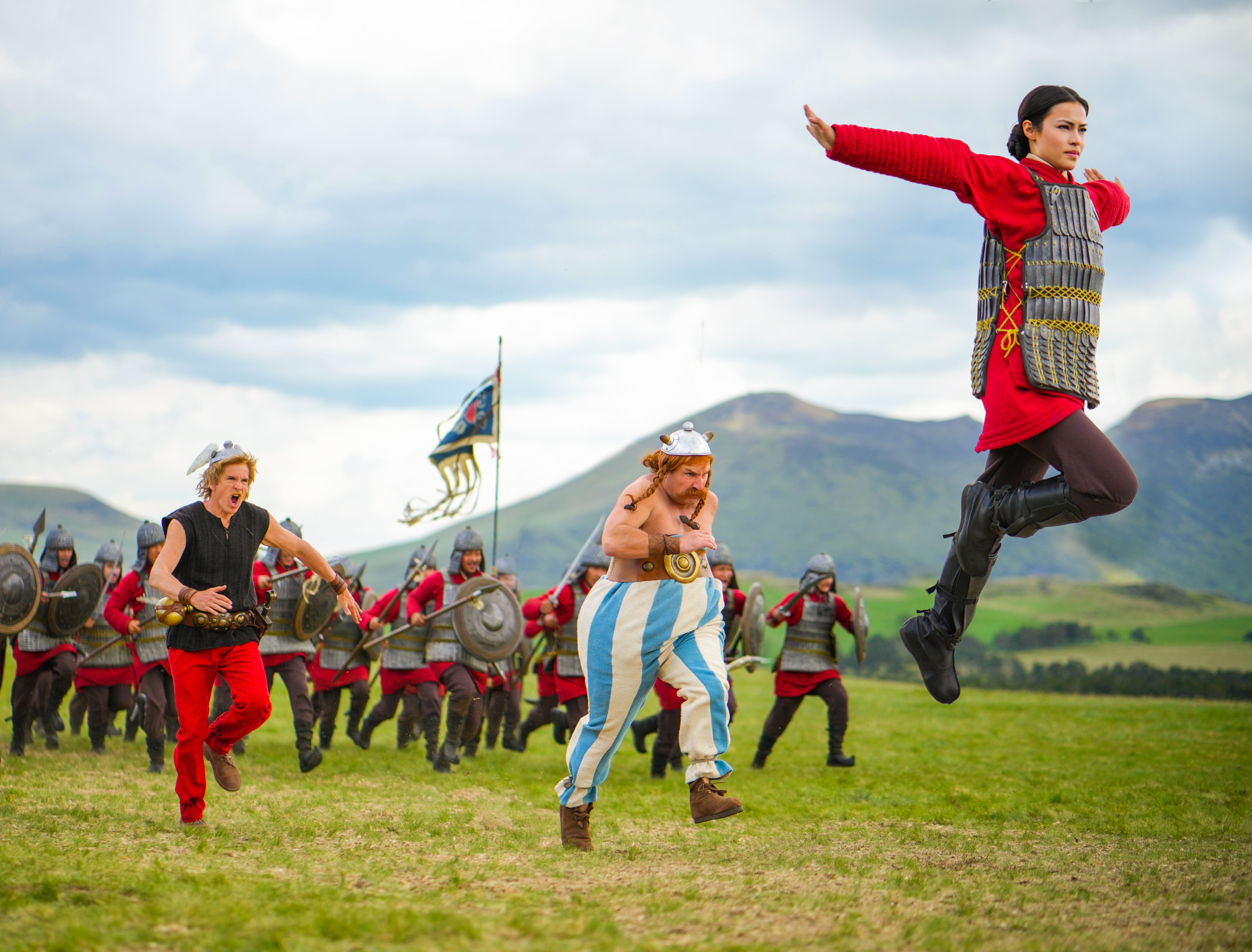 Eine Gruppe von Leuten auf einem Feld; einige rennen, einer springt, einer trägt einen Kriegerhelm.