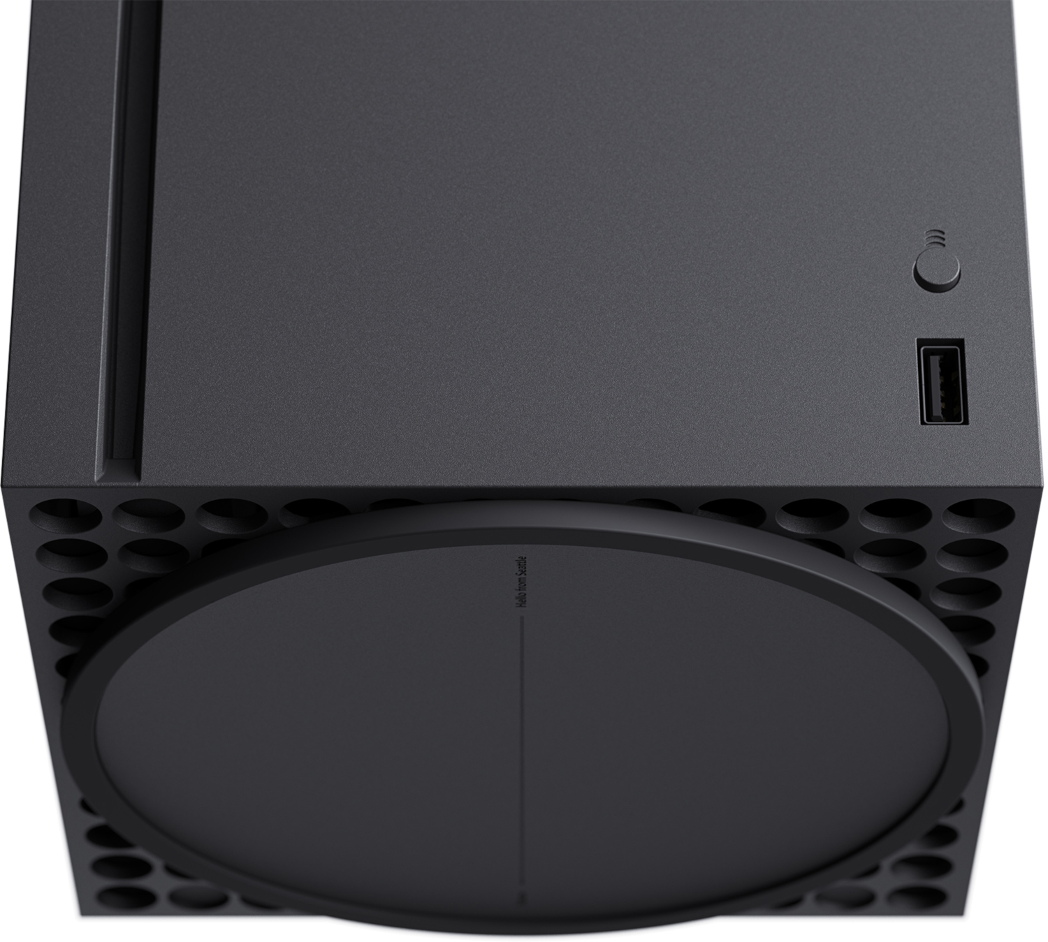 Een close-up van een zwarte Xbox Series X console. Het heeft een aan/uit-knop, een USB-poort en een schijfstation. De console staat op een wit oppervlak.