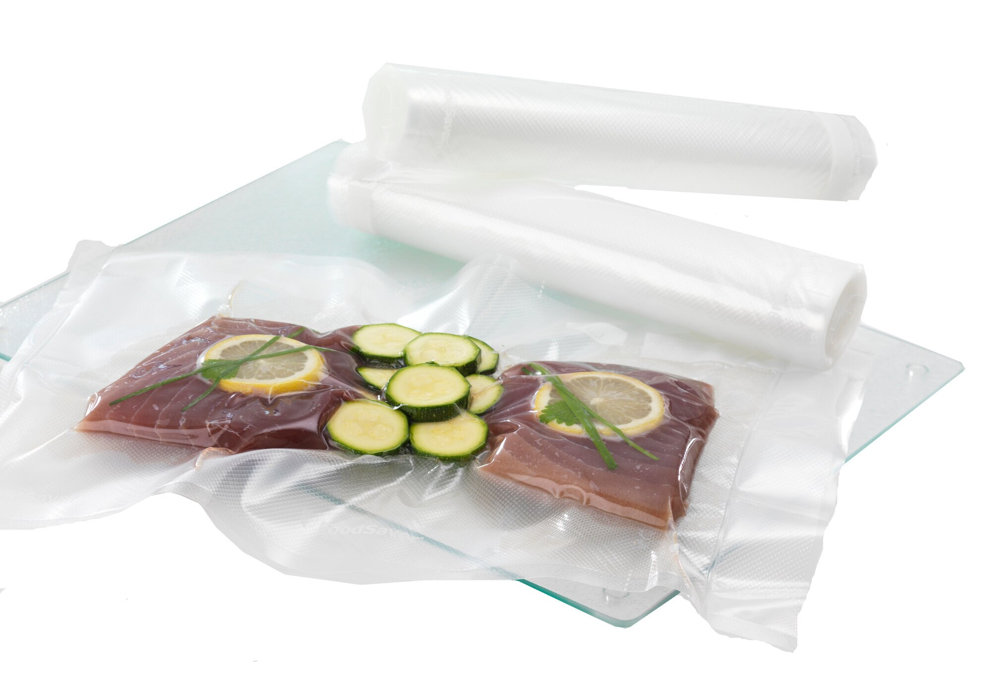 Żywność zapieczętowana w workach próżniowych, pokrojone warzywa, plasterki cytryny. Białe tło.