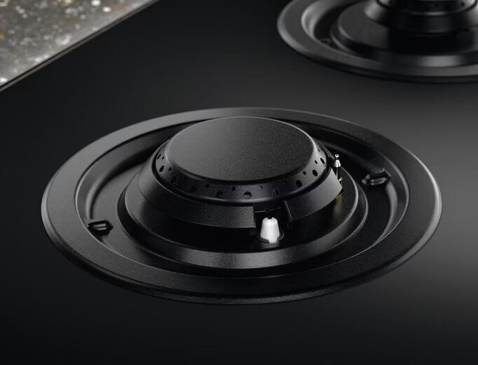 Zbliżenie czarnego palnika kuchenki z okrągłym wzorem.