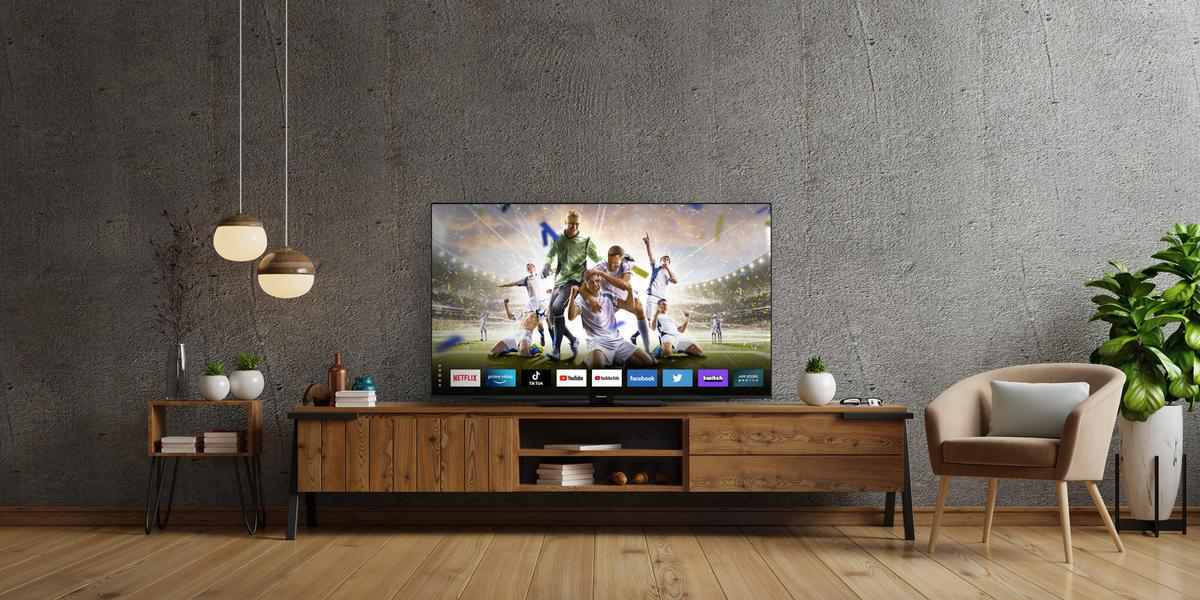 Wohnzimmer mit Fernseher, Holzschrank, graue Wand, Hängelampen, Pflanze.