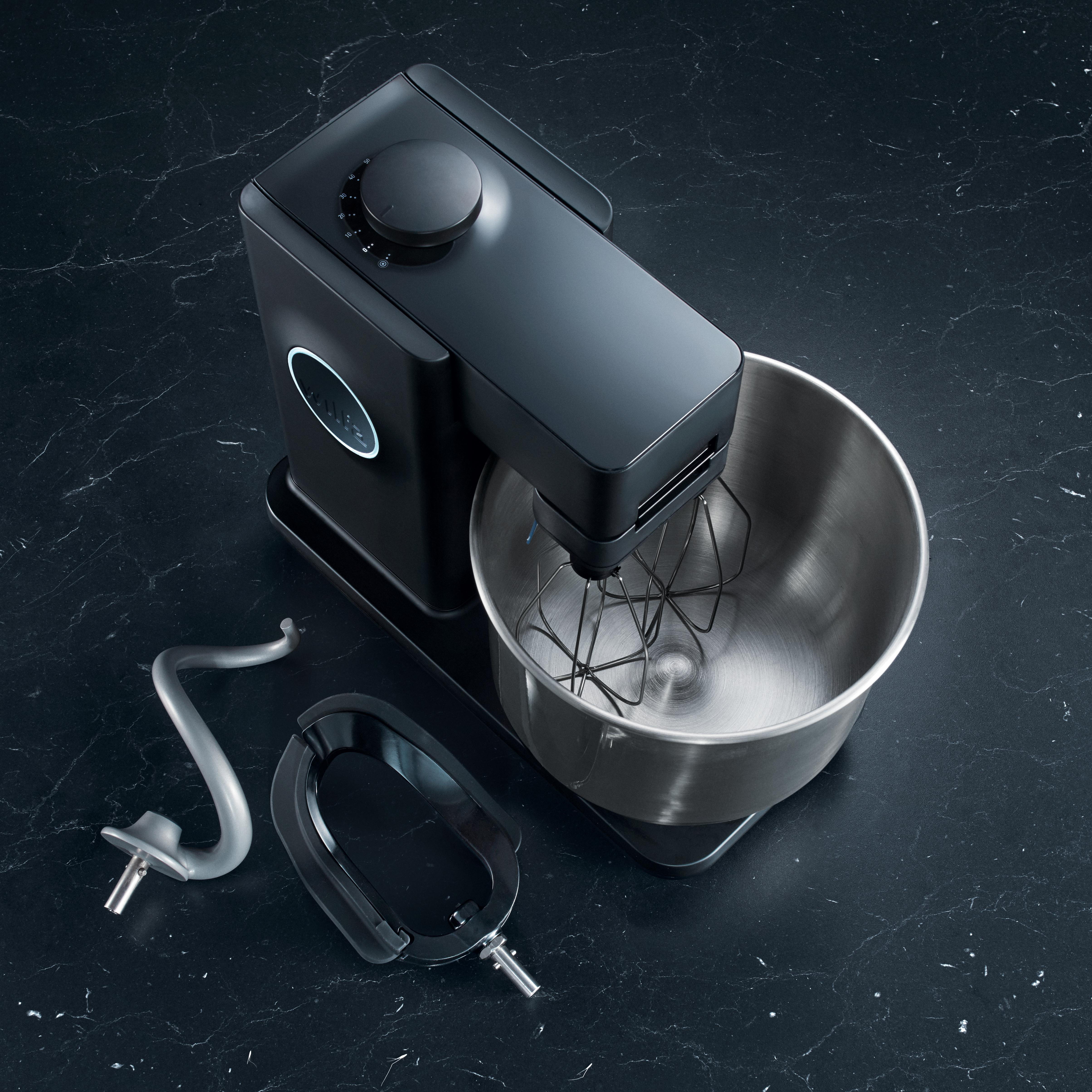 Schwarzer Küchenmixer mit Aufsätzen auf dunkler Marmoroberfläche. Der Mixer ist Edelstahl.