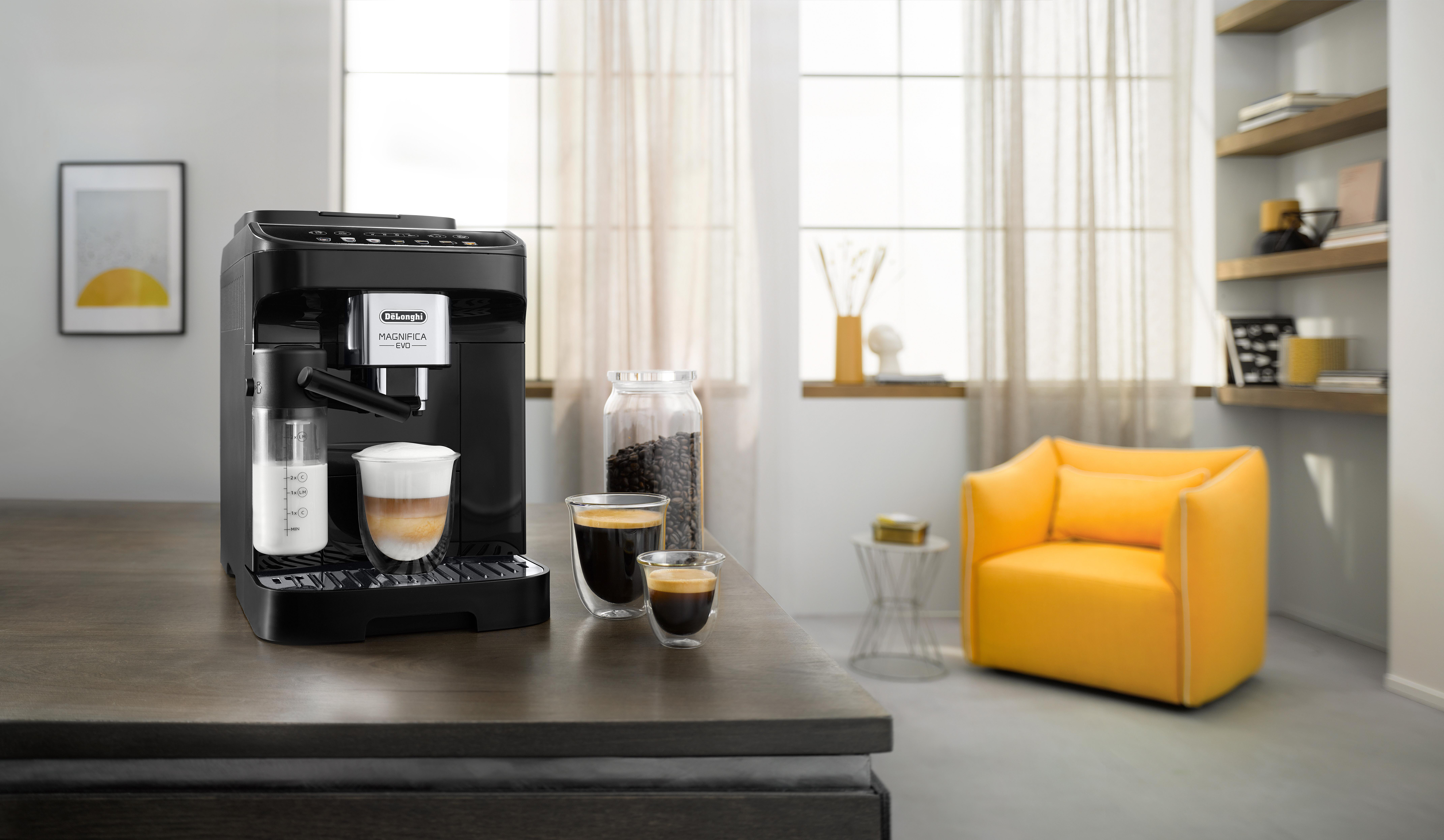 Schwarze DeLonghi Espressomaschine, Kaffeetassen, Milchkanne, Bohnenglas, gelber Stuhl.