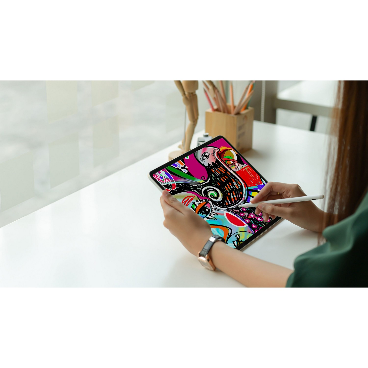 Une personne utilisant une tablette avec un stylet, affichant une œuvre d'art abstraite colorée sur une table blanche.
