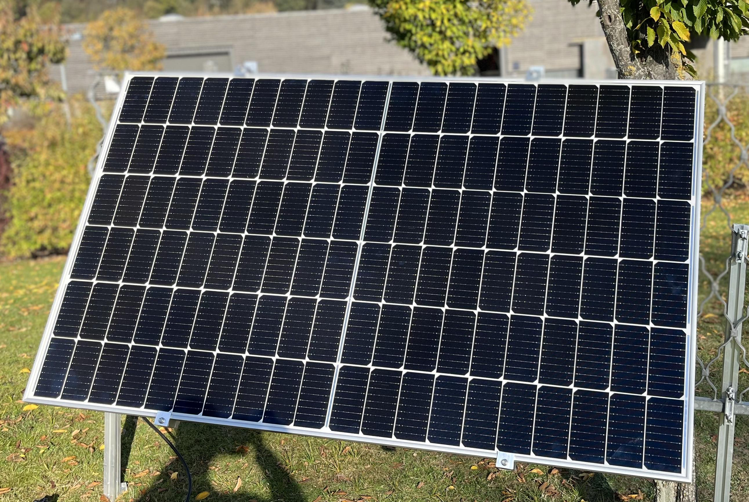 Ein Solarpanel auf einem Metallrahmen in einem grasbewachsenen Garten.