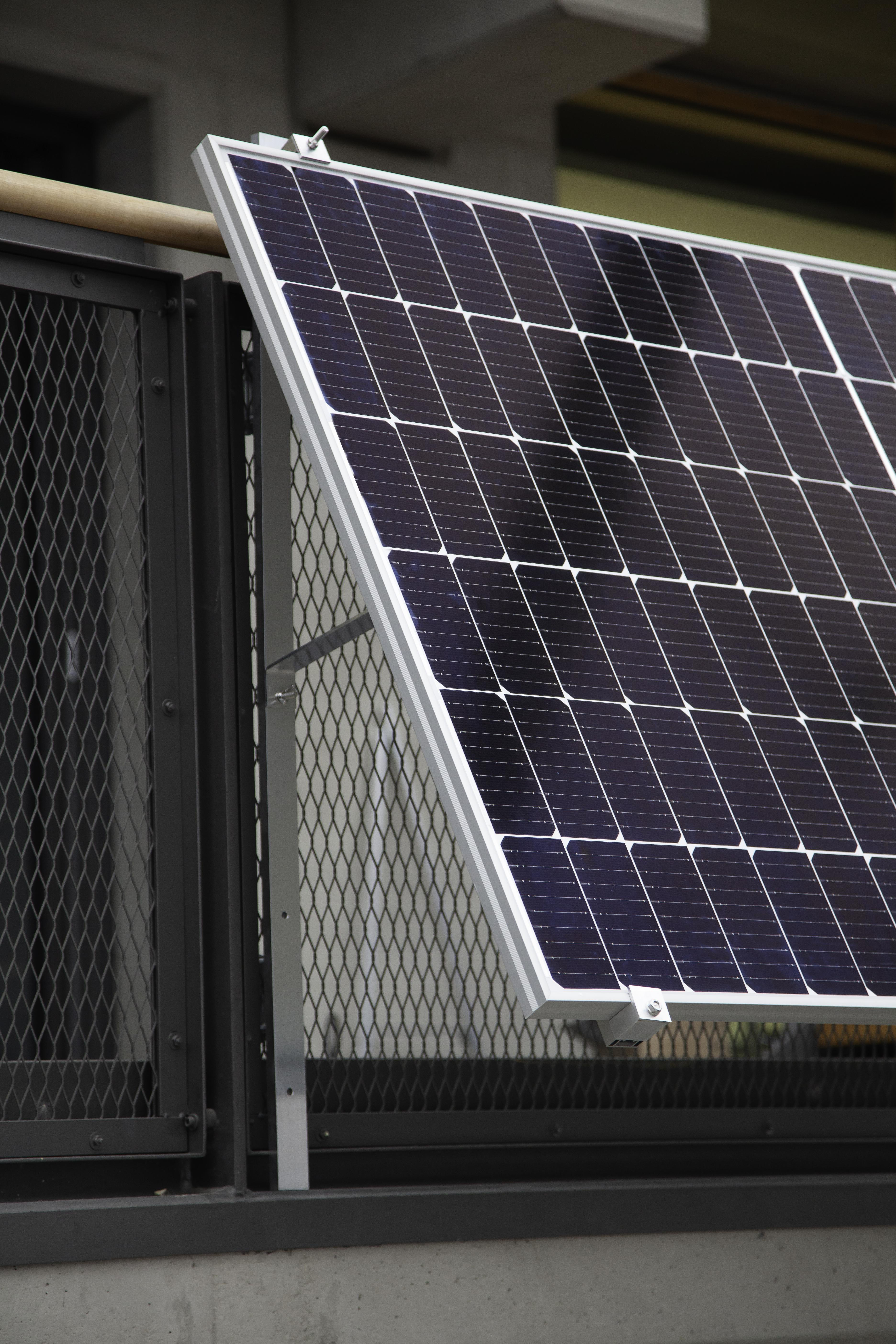 Solarpanel auf Metallstruktur montiert, vor Gebäude mit Zaun.