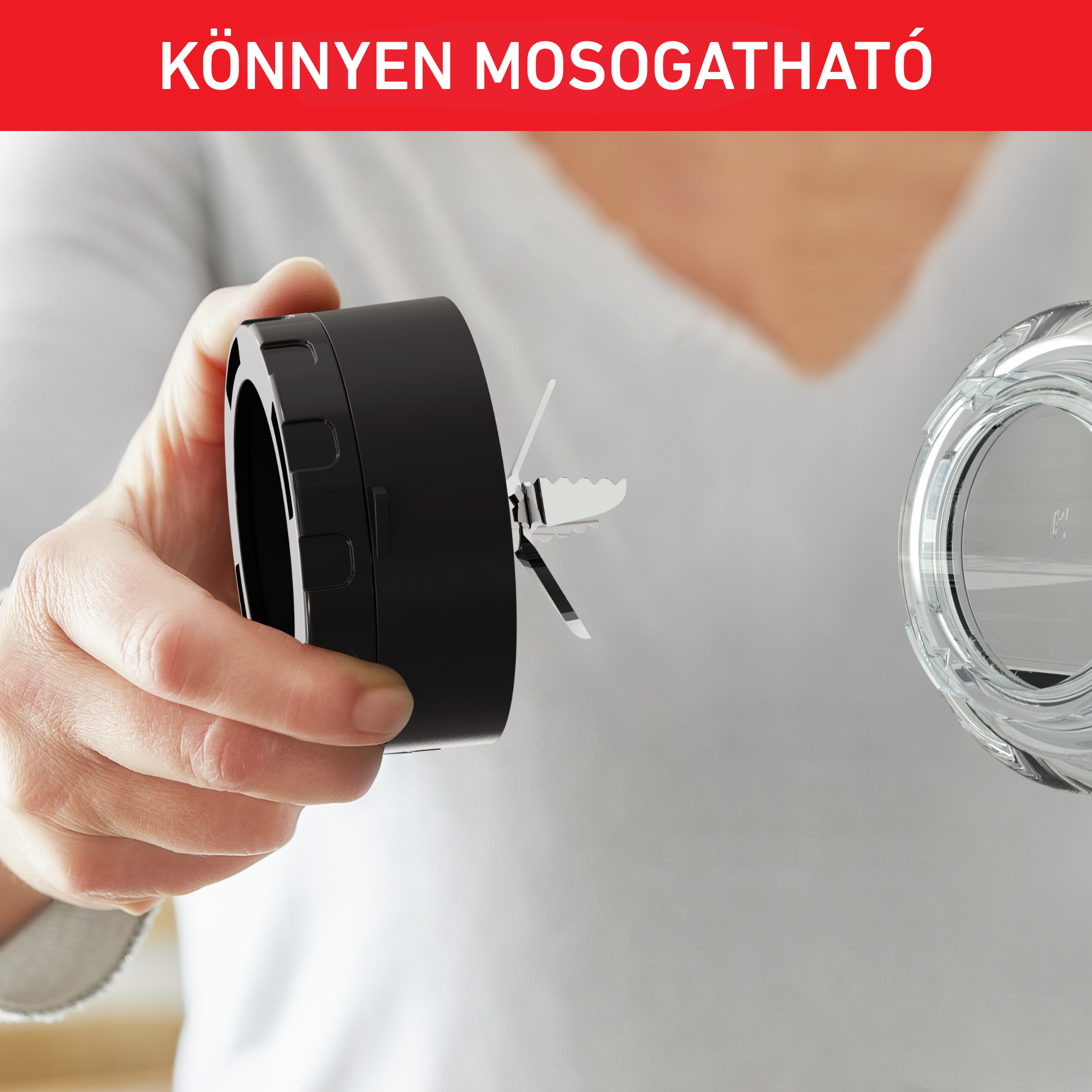 Egy személy keze egy fekete turmixgép pengéjét tartja egy átlátszó üvegtartály mellett.
