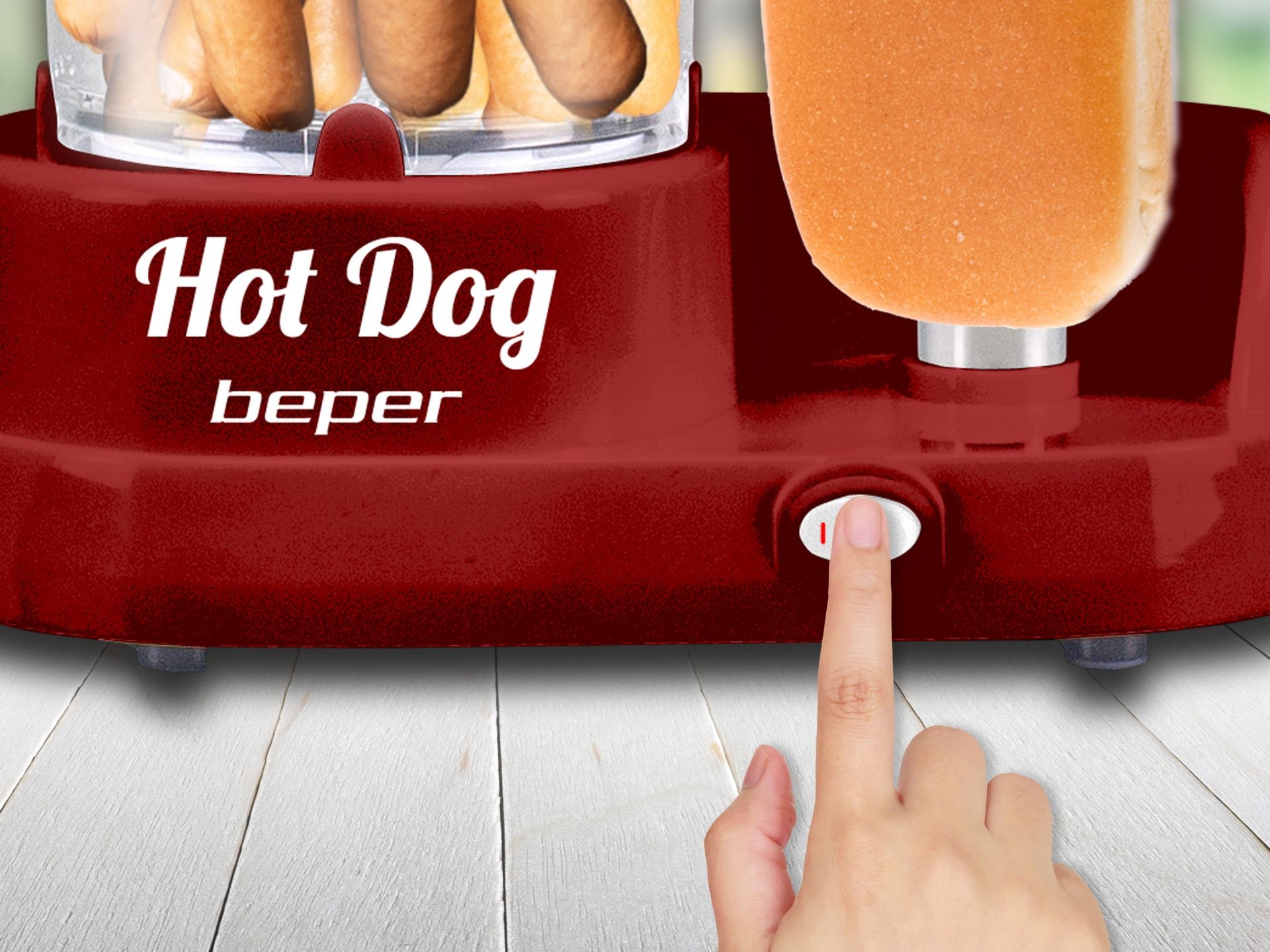 Piros hot dog gép, ujj a kapcsolón. Hot dogok belül.