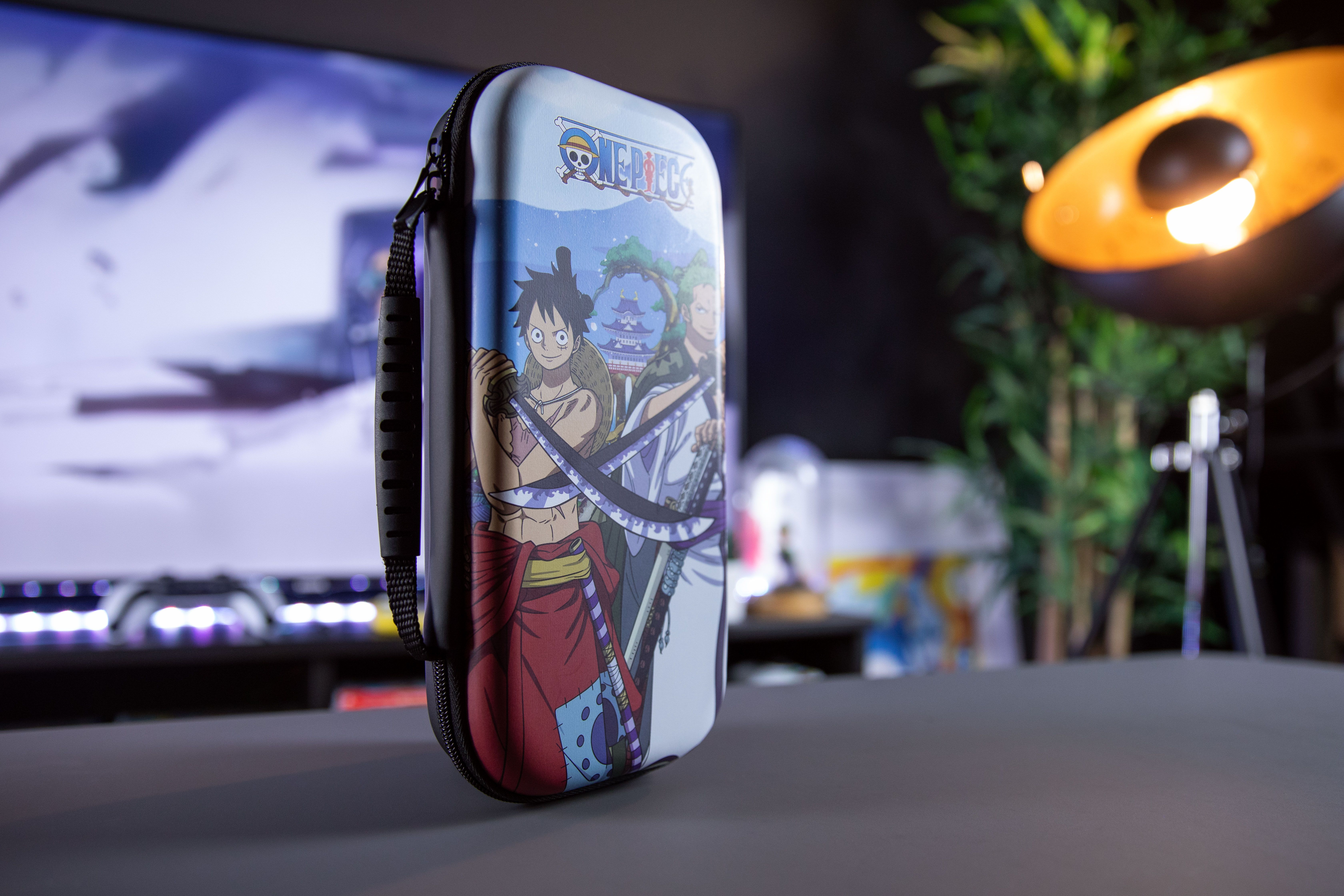 Eine schwarze Hülle mit den One Piece Anime-Charakteren darauf. Es liegt auf einem Tisch.
