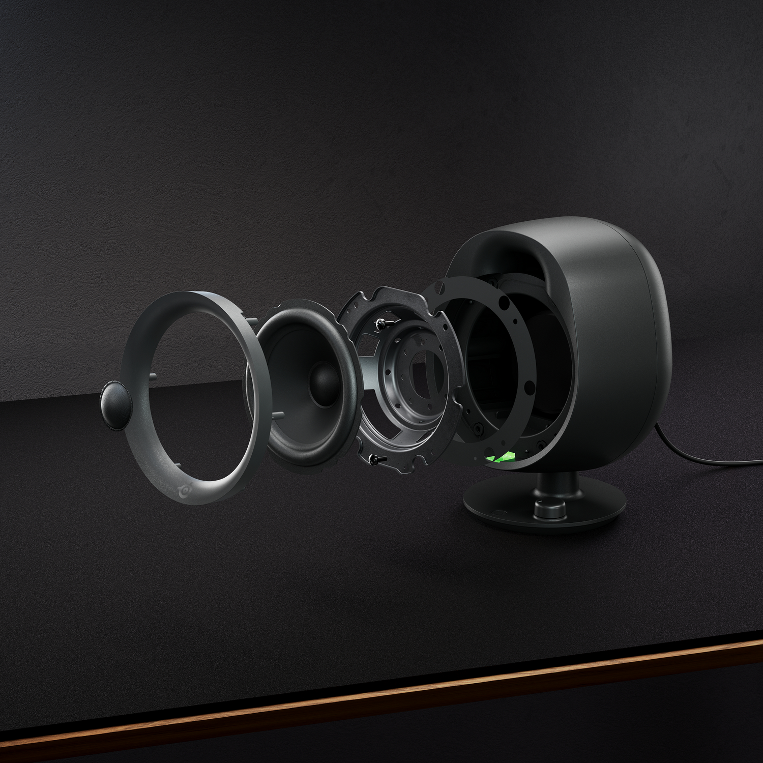 Speaker components exploded view on dark surface. A green light is on.