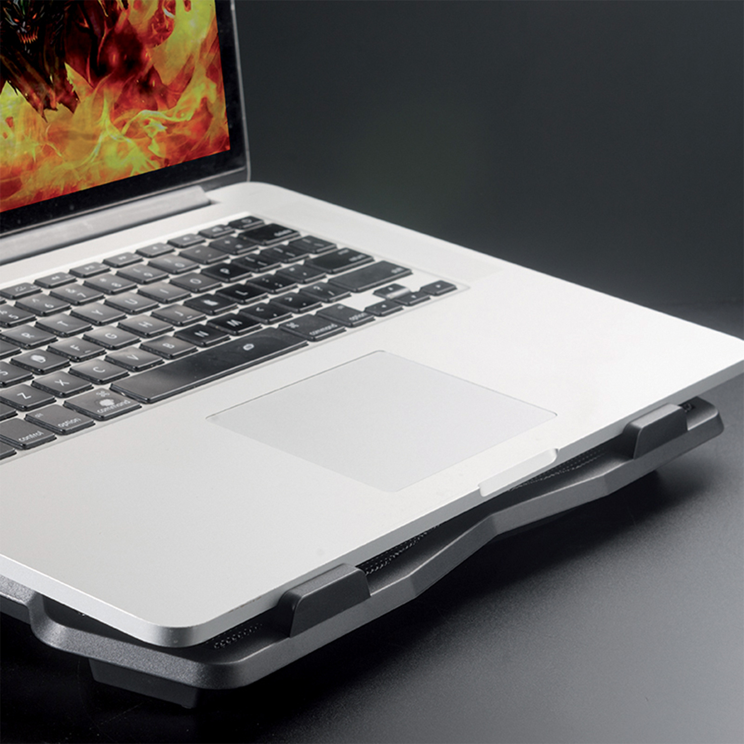Un laptop su un supporto di raffreddamento, che mostra uno schermo con una grafica infuocata.