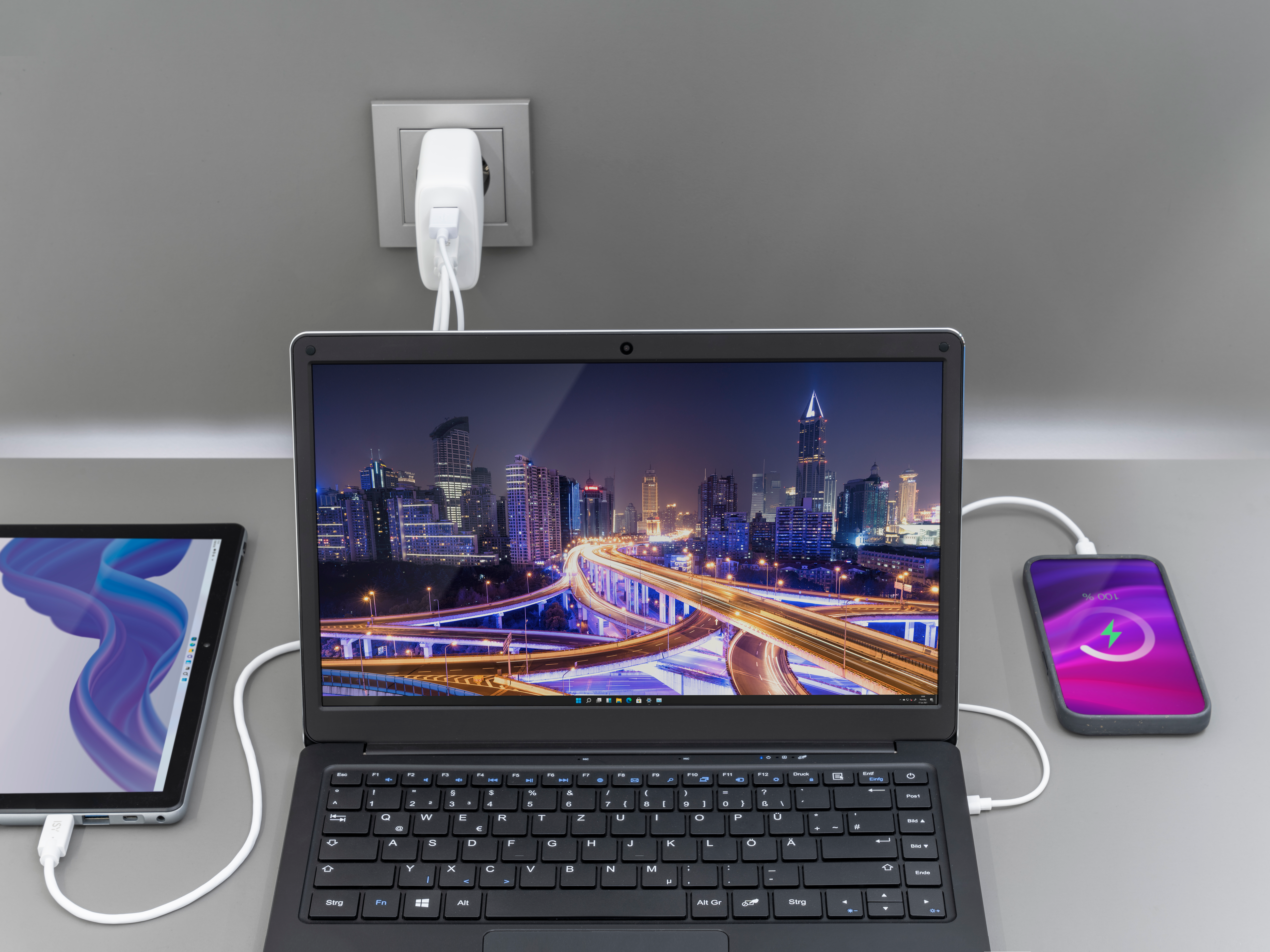 Dispositivi in carica: tablet, laptop e telefono. Il telefono mostra un indicatore di carica.