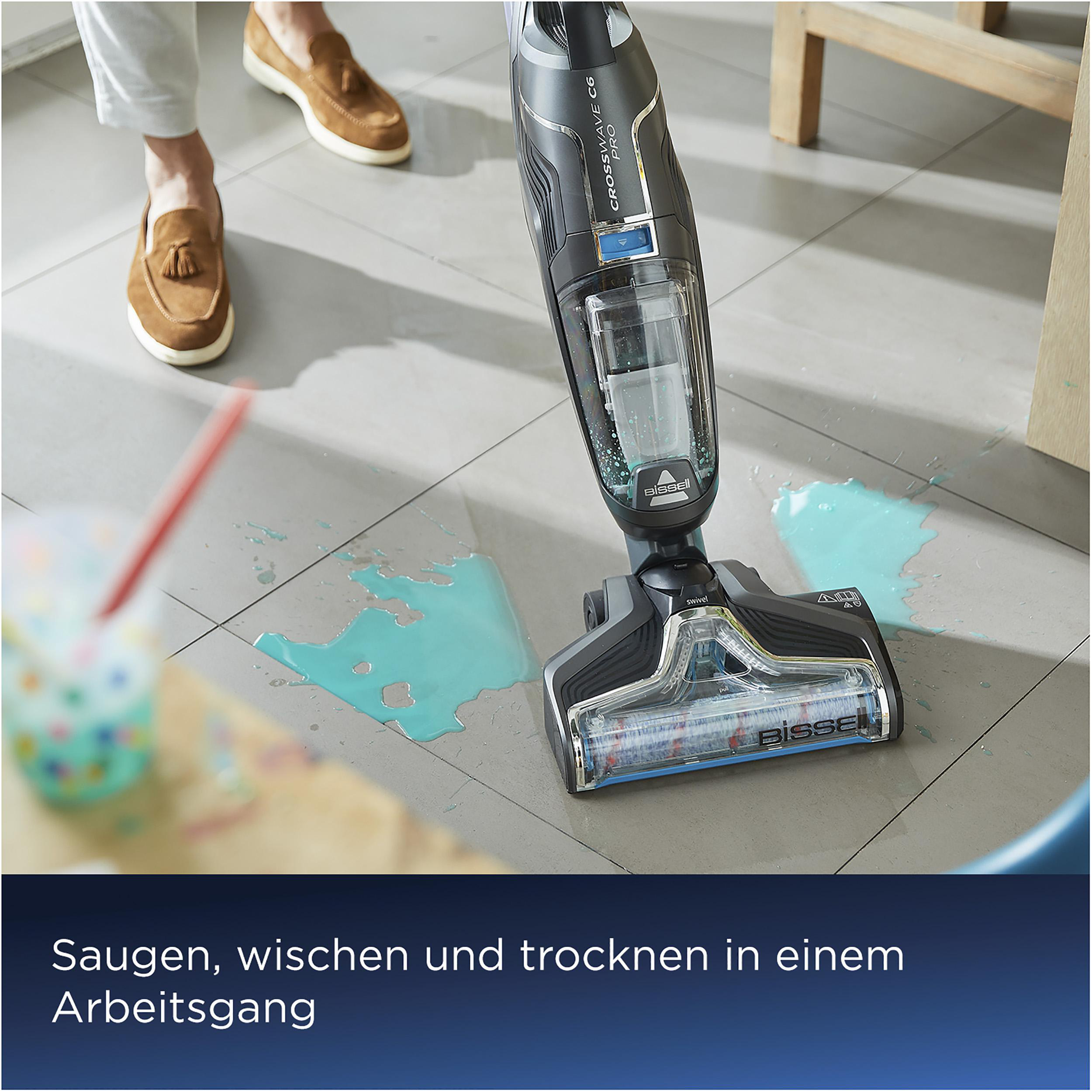 Eine Person benutzt einen Staubsauger auf nassem Boden, um verschüttetes Wasser zu reinigen.