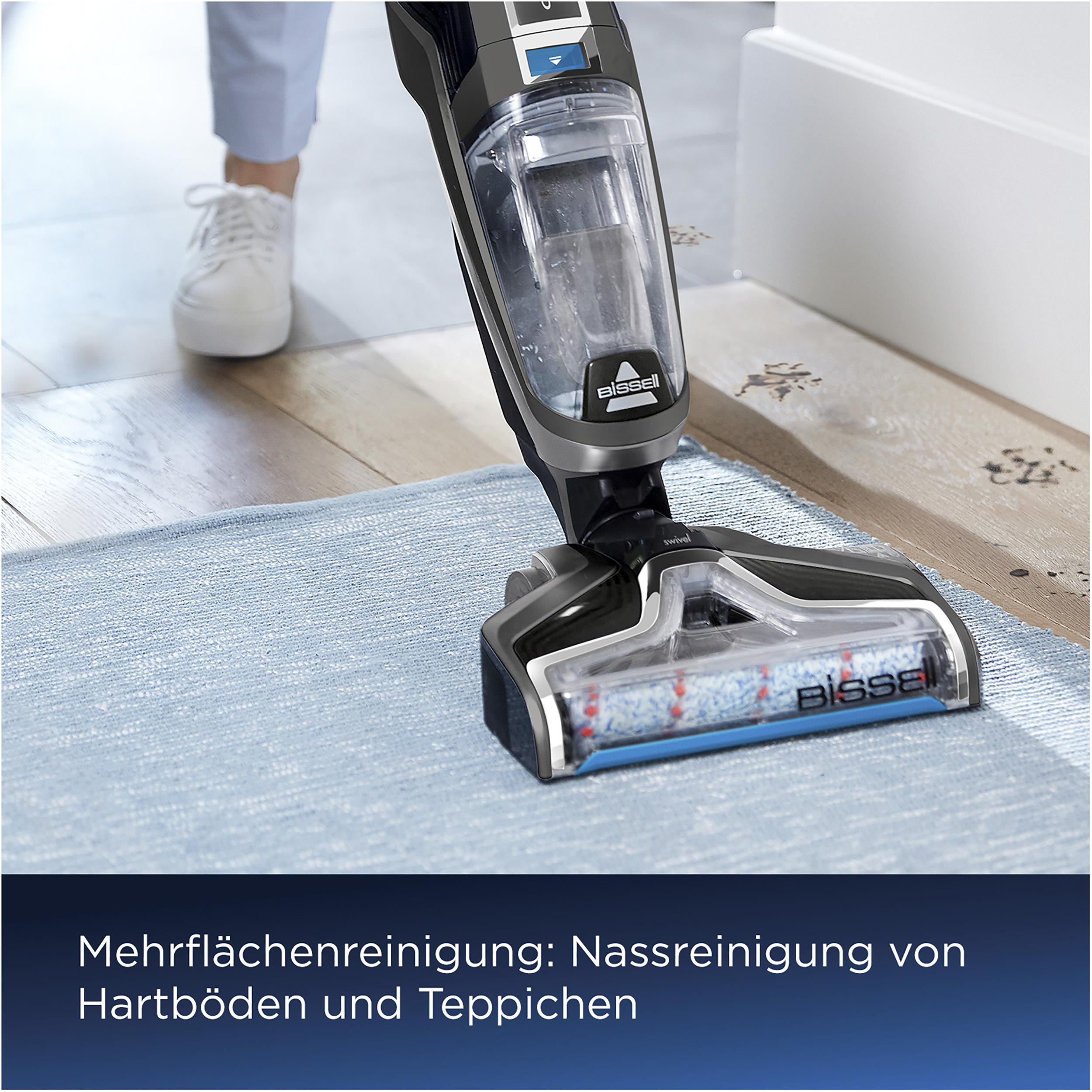 Person verwendet Bissell-Reiniger auf blauem Teppich. Der Reiniger ist nah an der Kamera.
