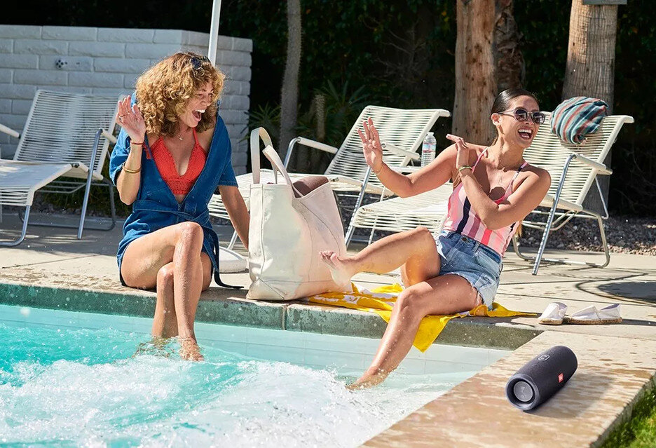 Dwie kobiety przy basenie. Jedna siedzi, druga chlapi wodą.