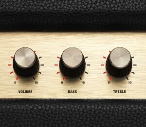 Zbliżenie złotego panelu wzmacniacza z pokrętłami głośności, basów i tonów wysokich.