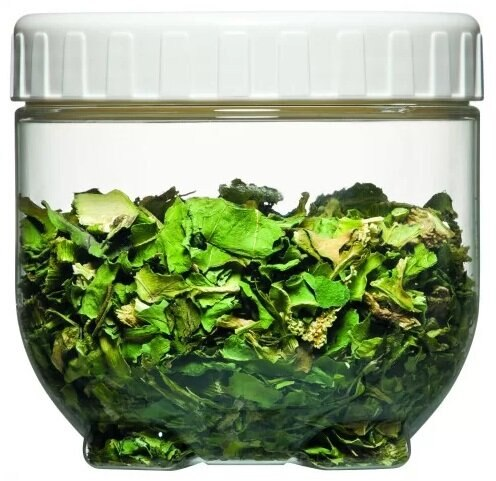 Przezroczysty słoik wypełniony zielonymi suszonymi liśćmi, na białym tle.