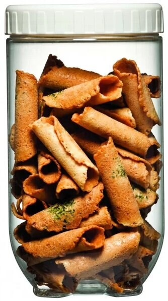 Przezroczysty słoik wypełniony zwiniętymi, brązowymi, chrupiącymi ciasteczkami.