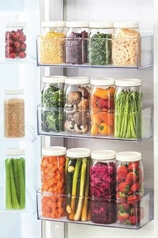 Lodówka z przezroczystymi słoikami z różnymi produktami, ułożonymi na półkach.