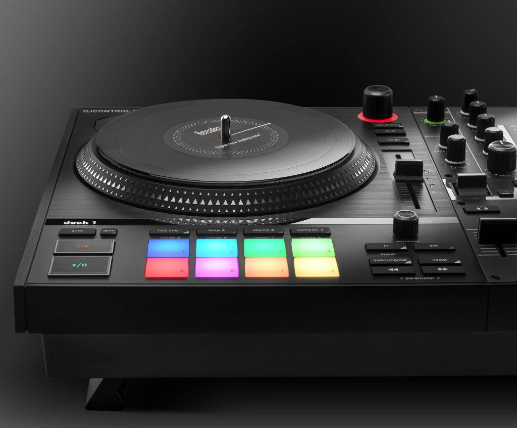 Ein DJ-Controller auf einer dunklen Oberfläche. Er hat einen Plattenspieler, Knöpfe und Regler, mit Fokus auf den beleuchteten Bedienelementen.