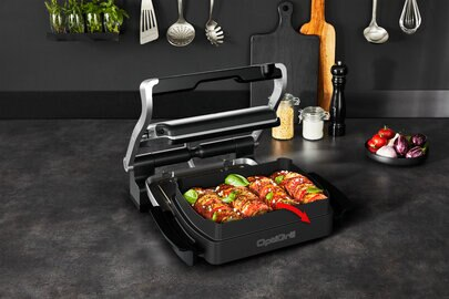 Czarny grill z tacą z jedzeniem, w kuchni z przyborami.