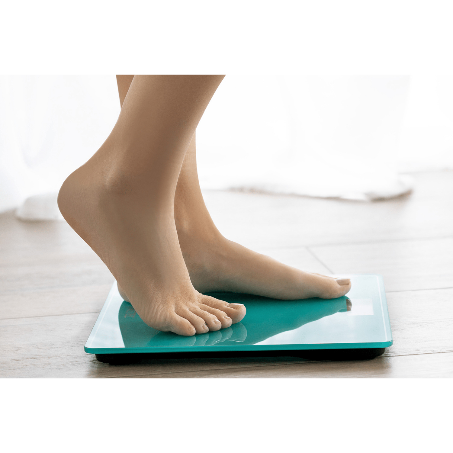 Piedi nudi su una bilancia turchese, con tende bianche sullo sfondo.