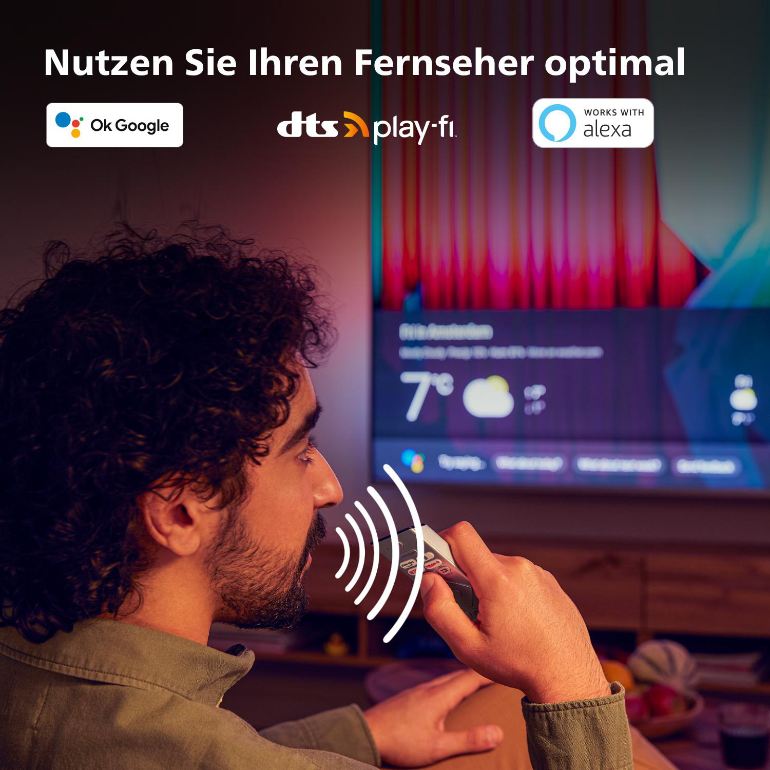 Mann spricht in Fernbedienung, TV zeigt Wetterinfo.