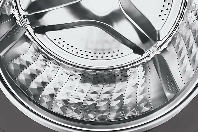 Zbliżenie wnętrza bębna ze stali nierdzewnej pralki.