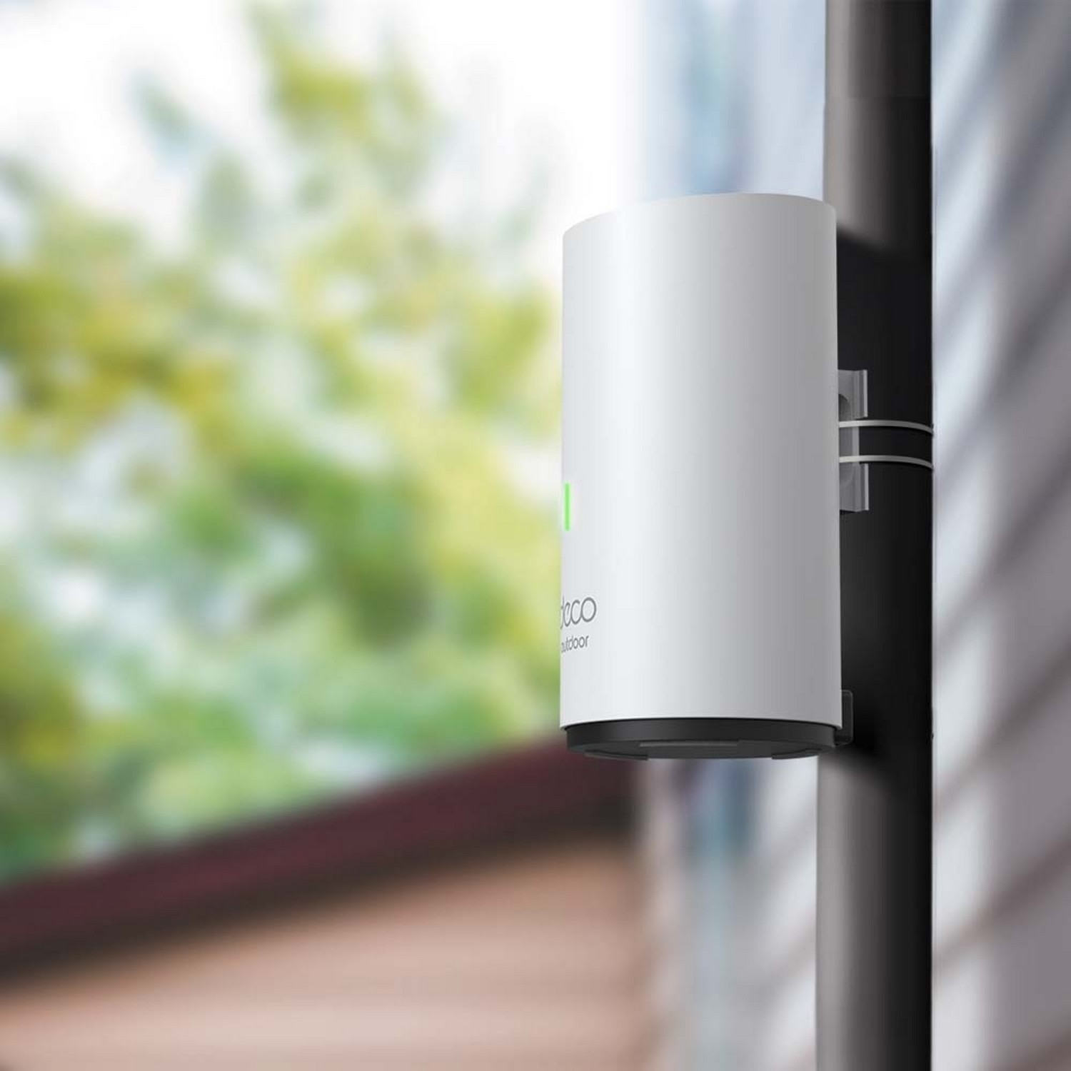 A white cylindrical outdoor wifi extender mounted on a pole, near greenery.