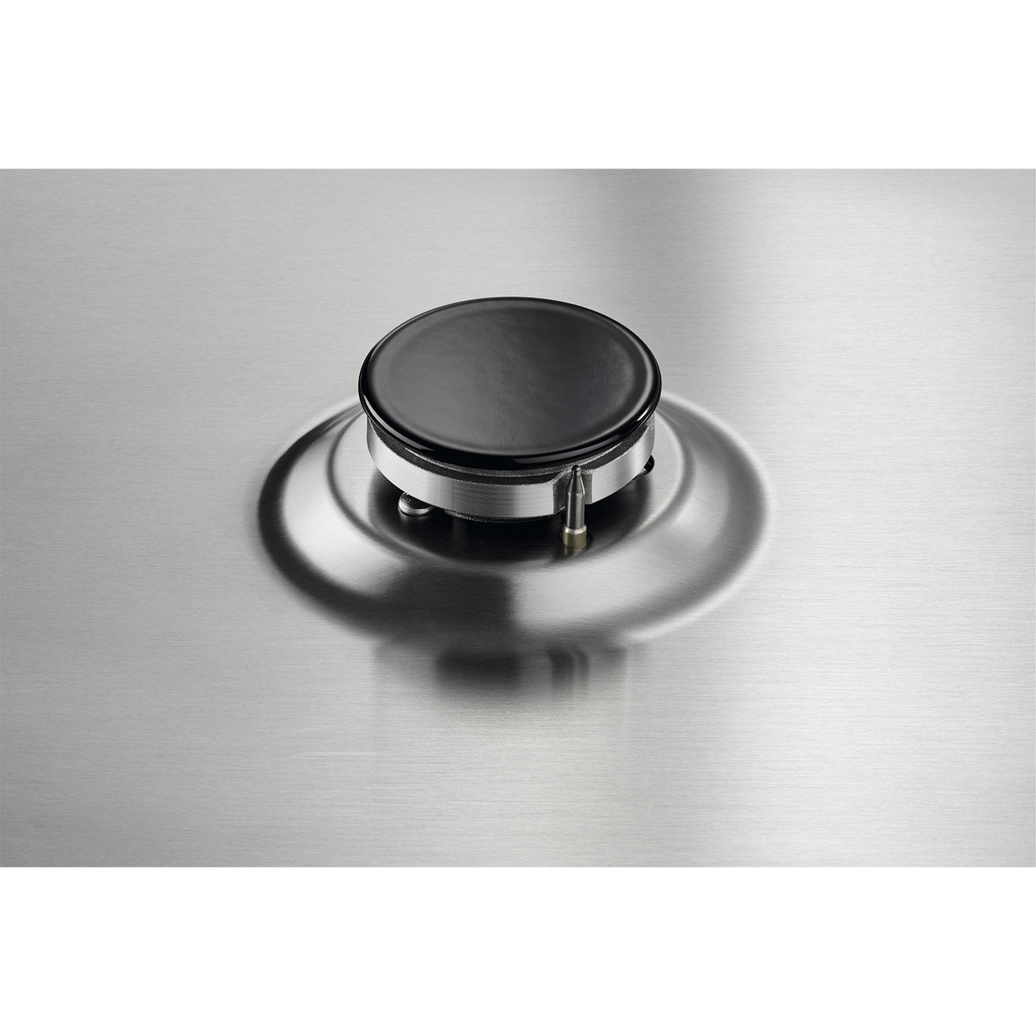 Primo piano di un bruciatore per fornelli a gas. Cappuccio nero del bruciatore su superficie in acciaio inox.