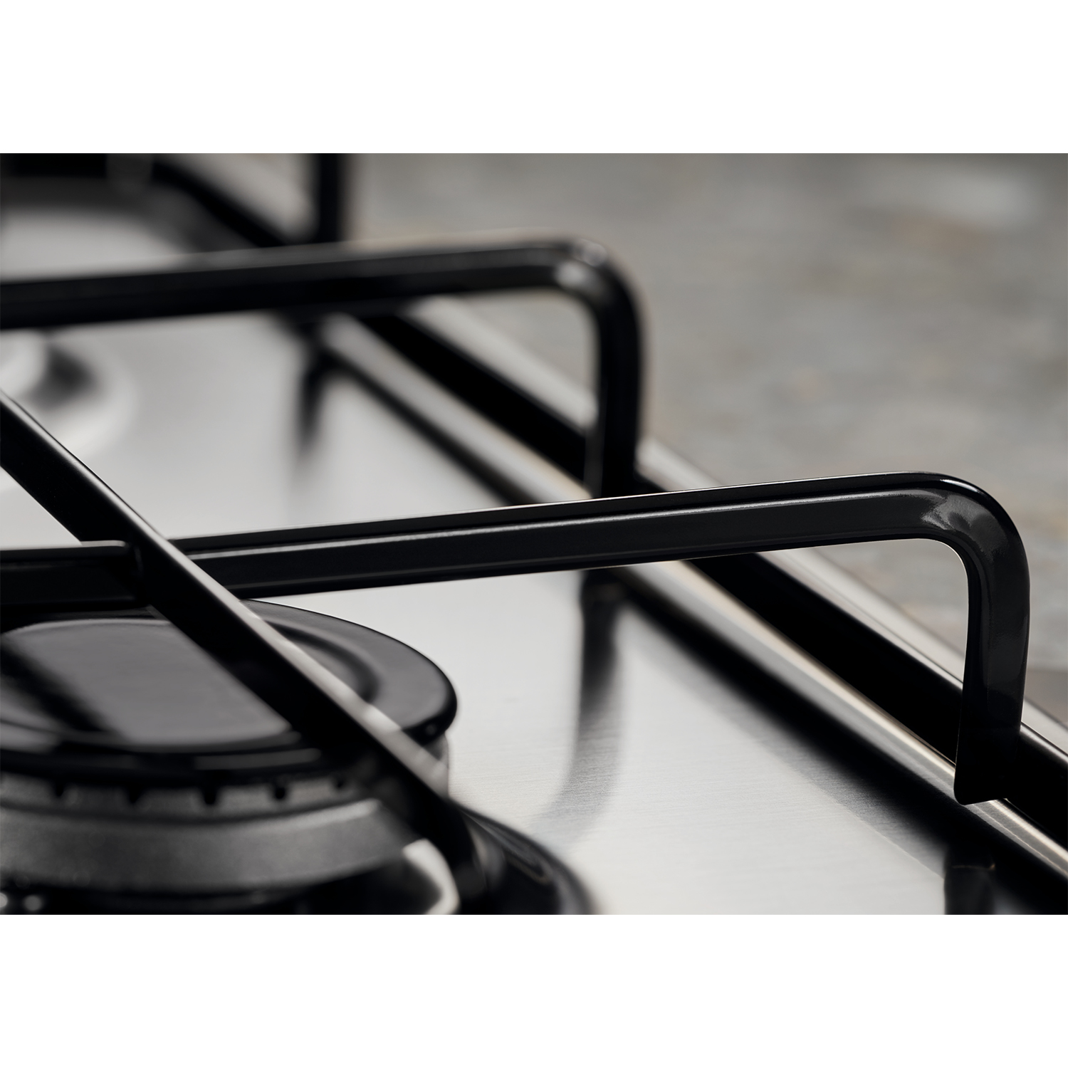 Primo piano dei bruciatori del fornello a gas, mostra griglie nere e un bruciatore. Superficie in acciaio inox.