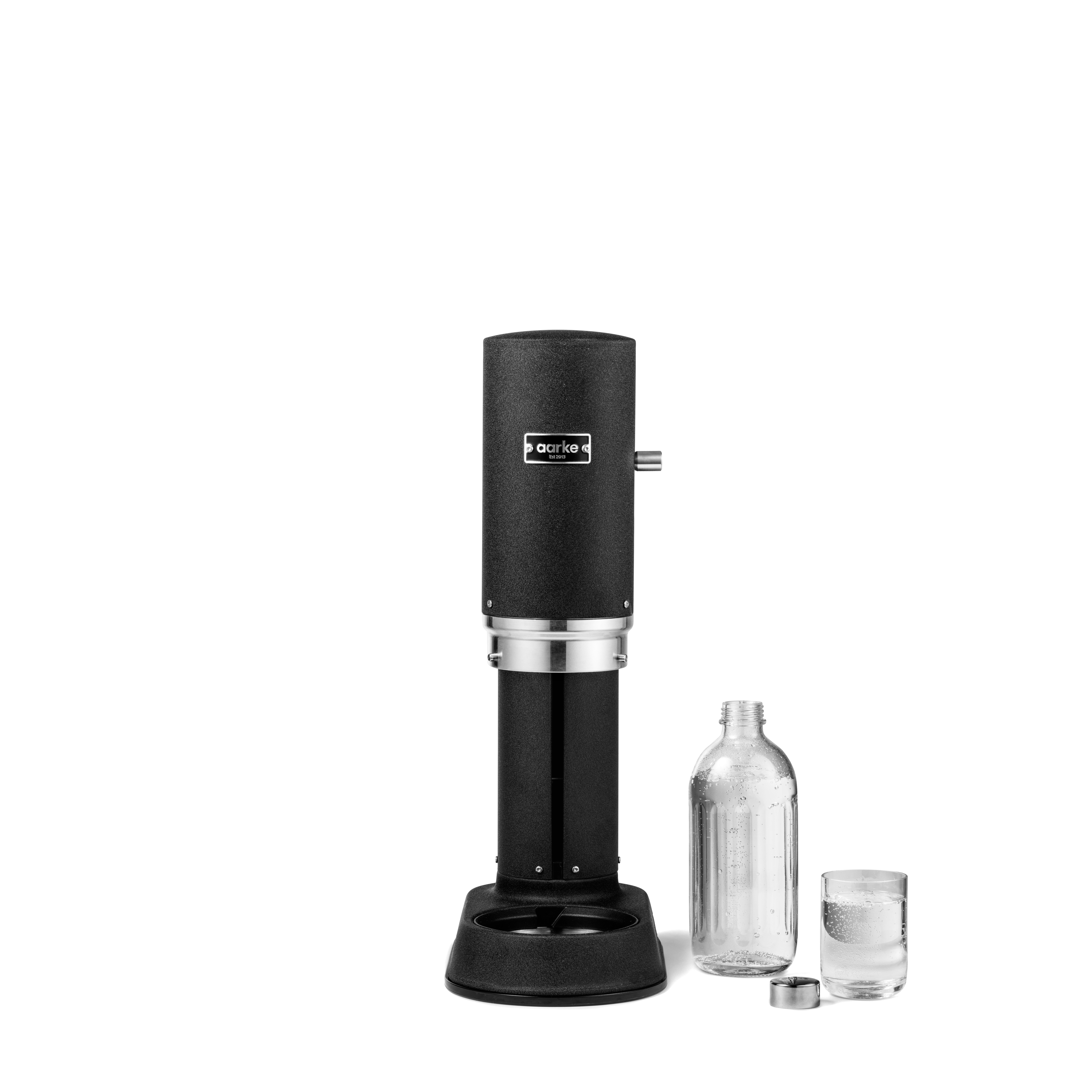 Schwarzer Soda-Maker mit Glasflasche und Glas Wasser. Weißer Hintergrund.